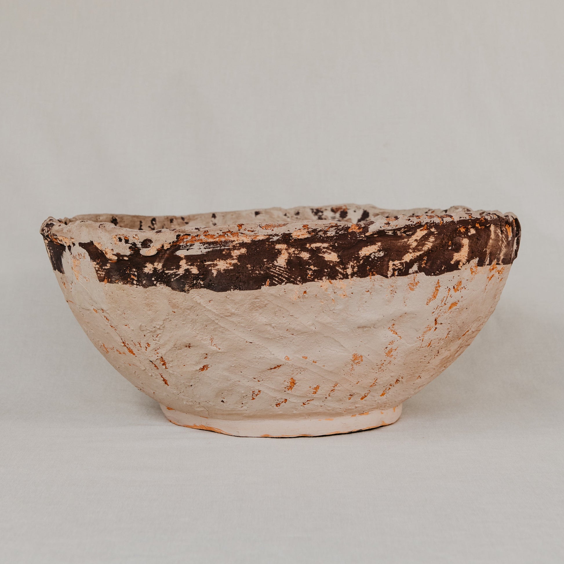 Ceramic bowl with brown and beige glaze on a plain background