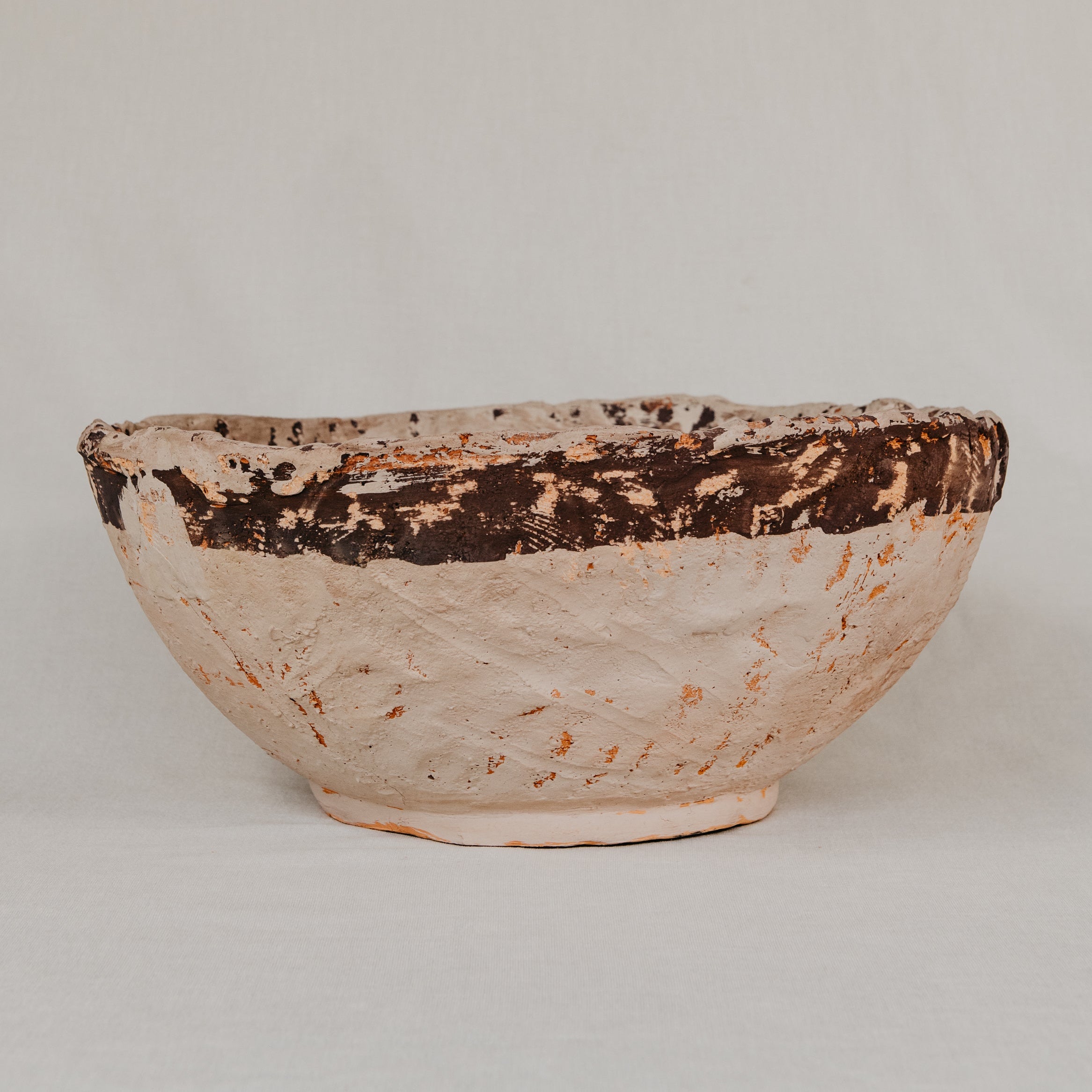 Ceramic bowl with brown and beige glaze on a plain background
