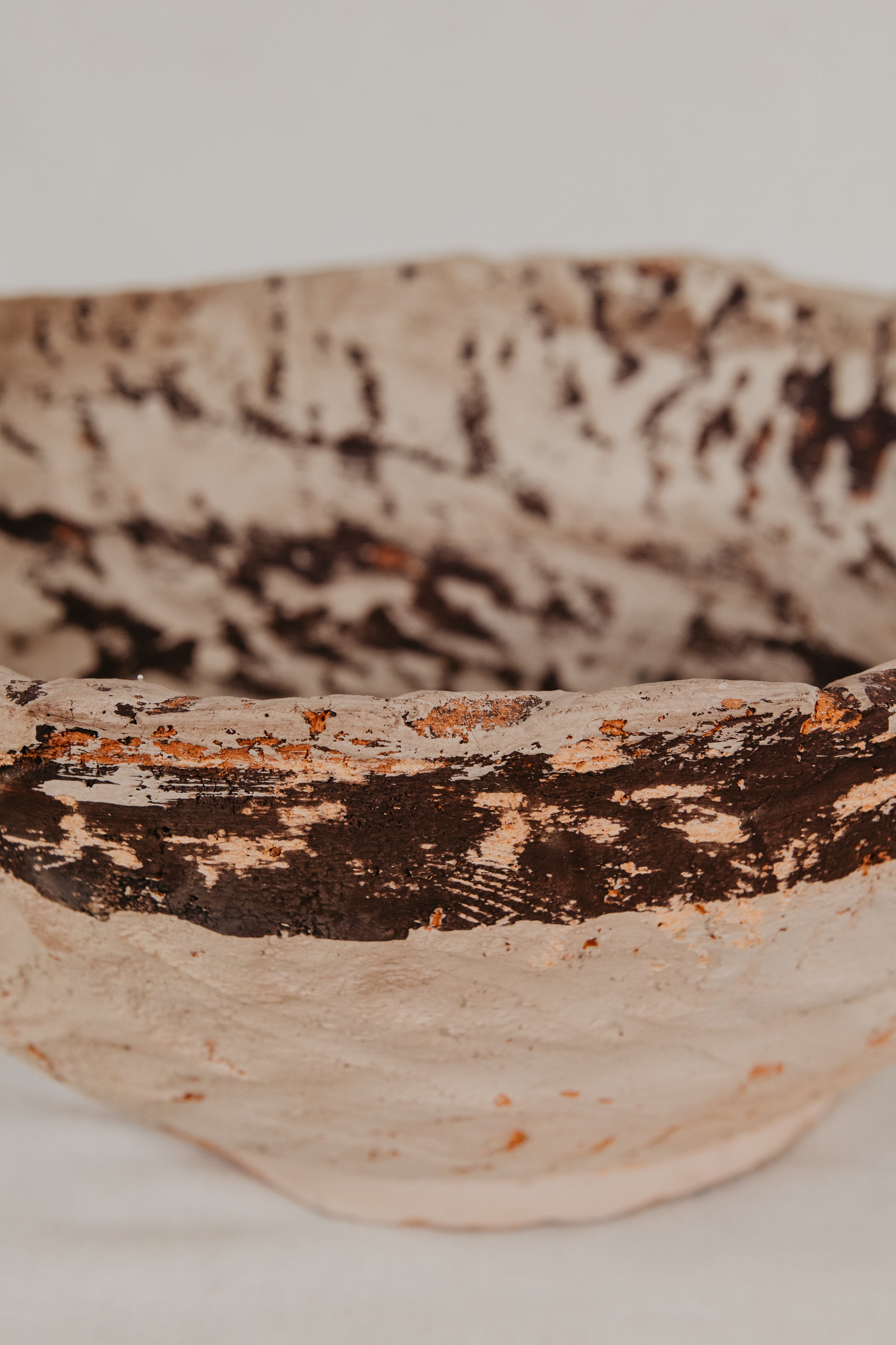 Close-up of a textured ceramic bowl with brown and beige patterns on a white background