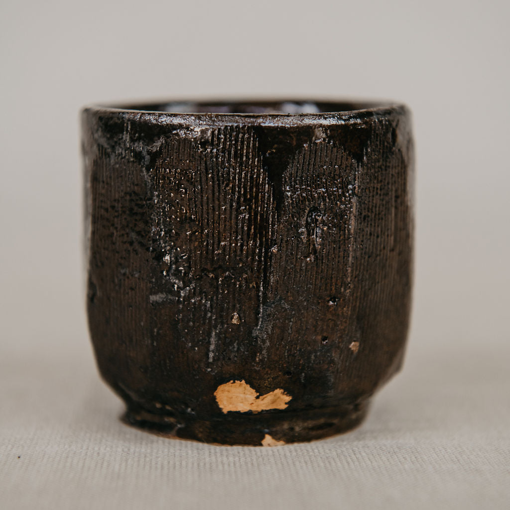 Black ceramic cup with textured surface on a light gray background