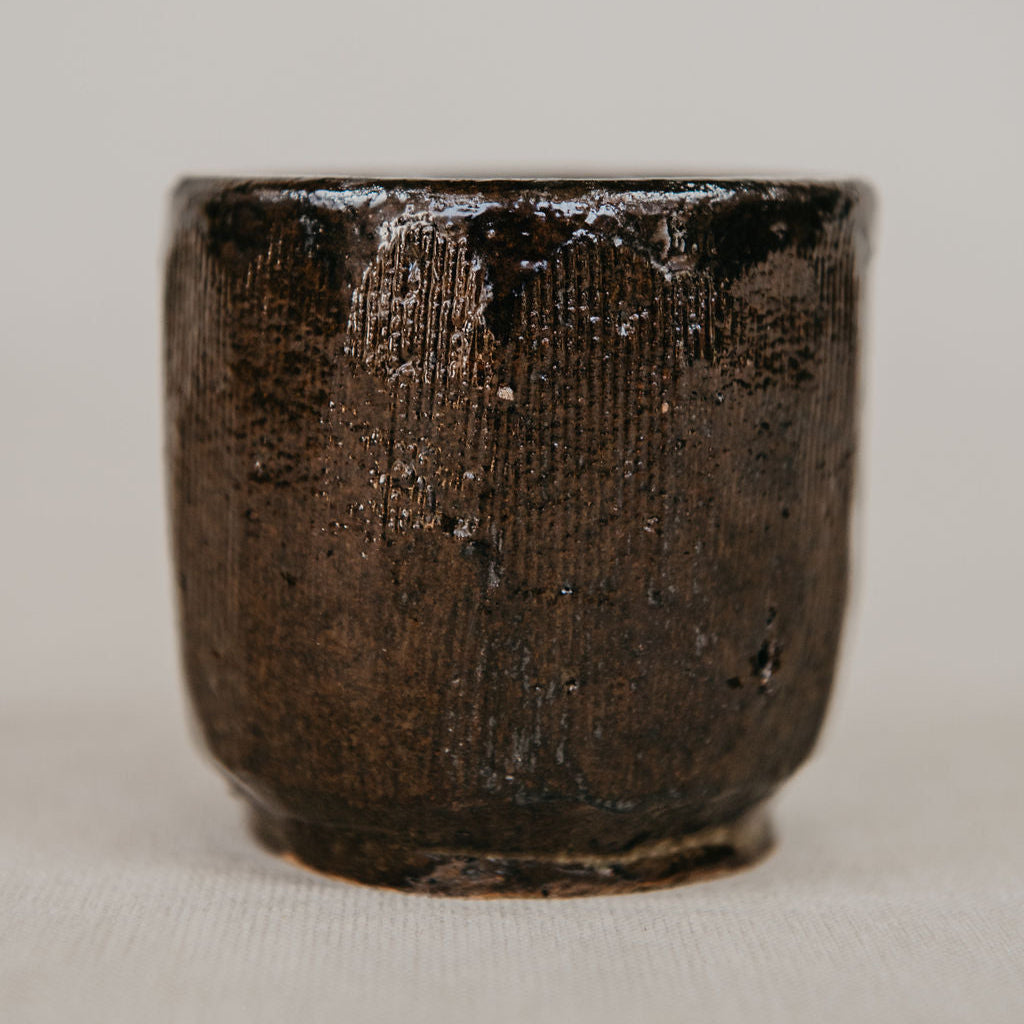 Dark brown ceramic cup on a light beige background
