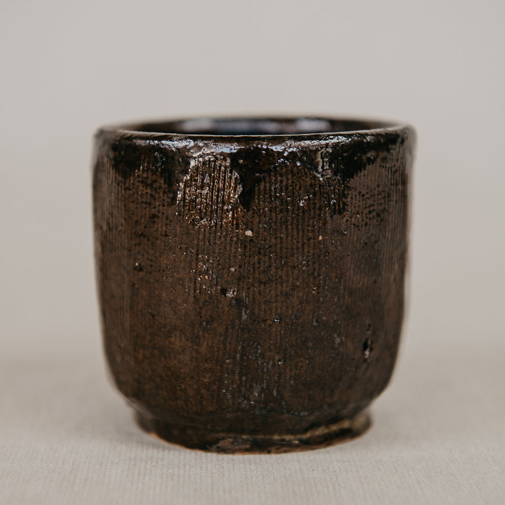 Dark brown ceramic cup on a light beige background