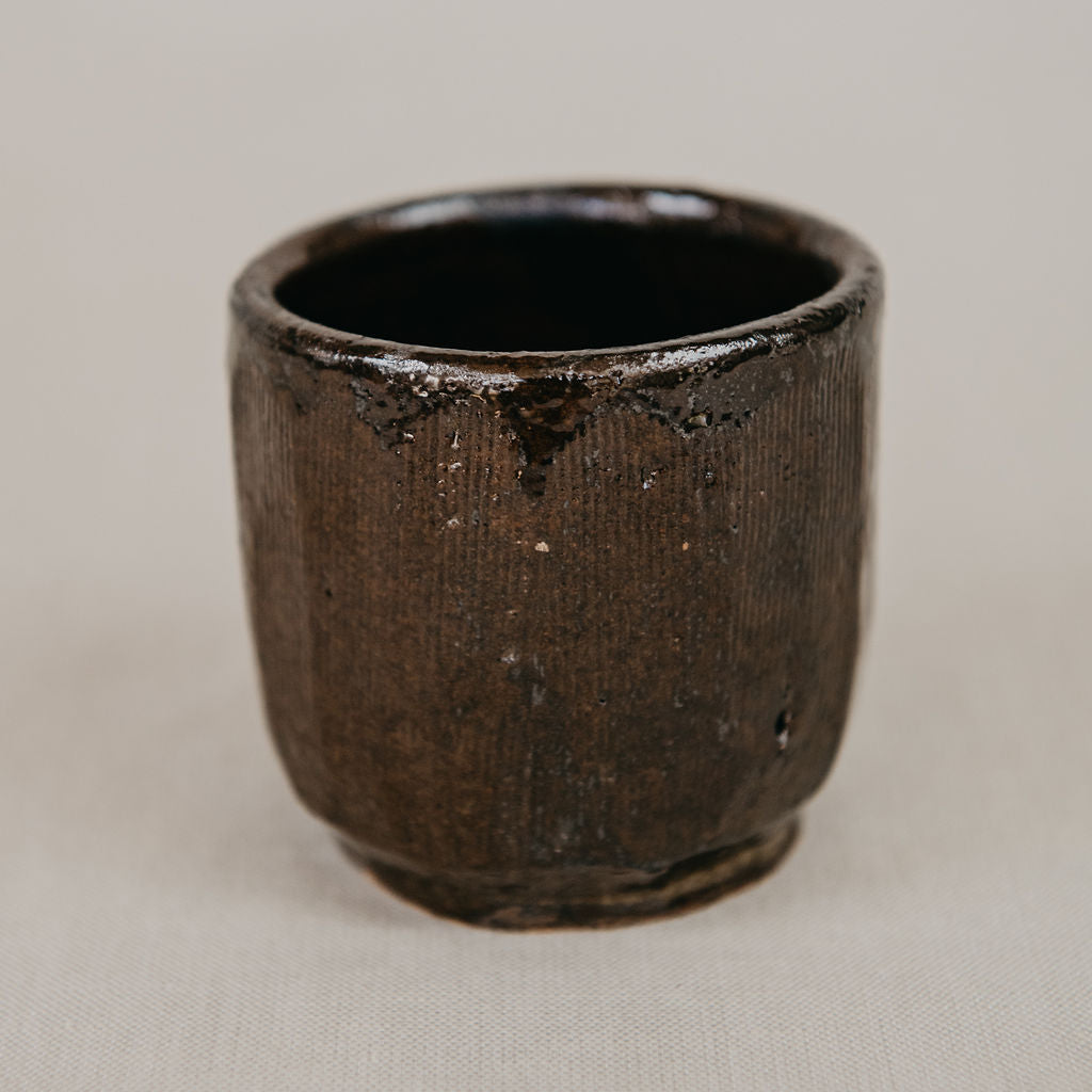 Dark brown ceramic cup on a beige background