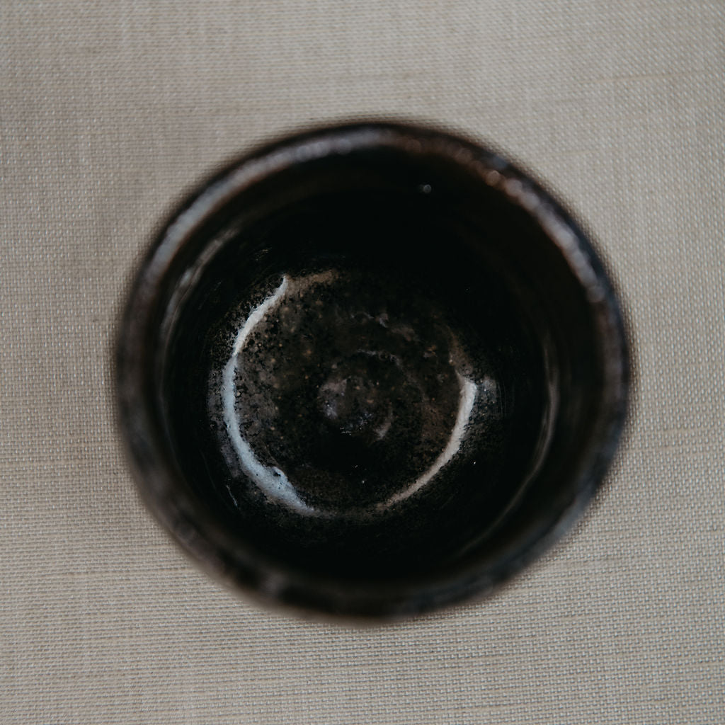 Black ceramic cup on a beige fabric background