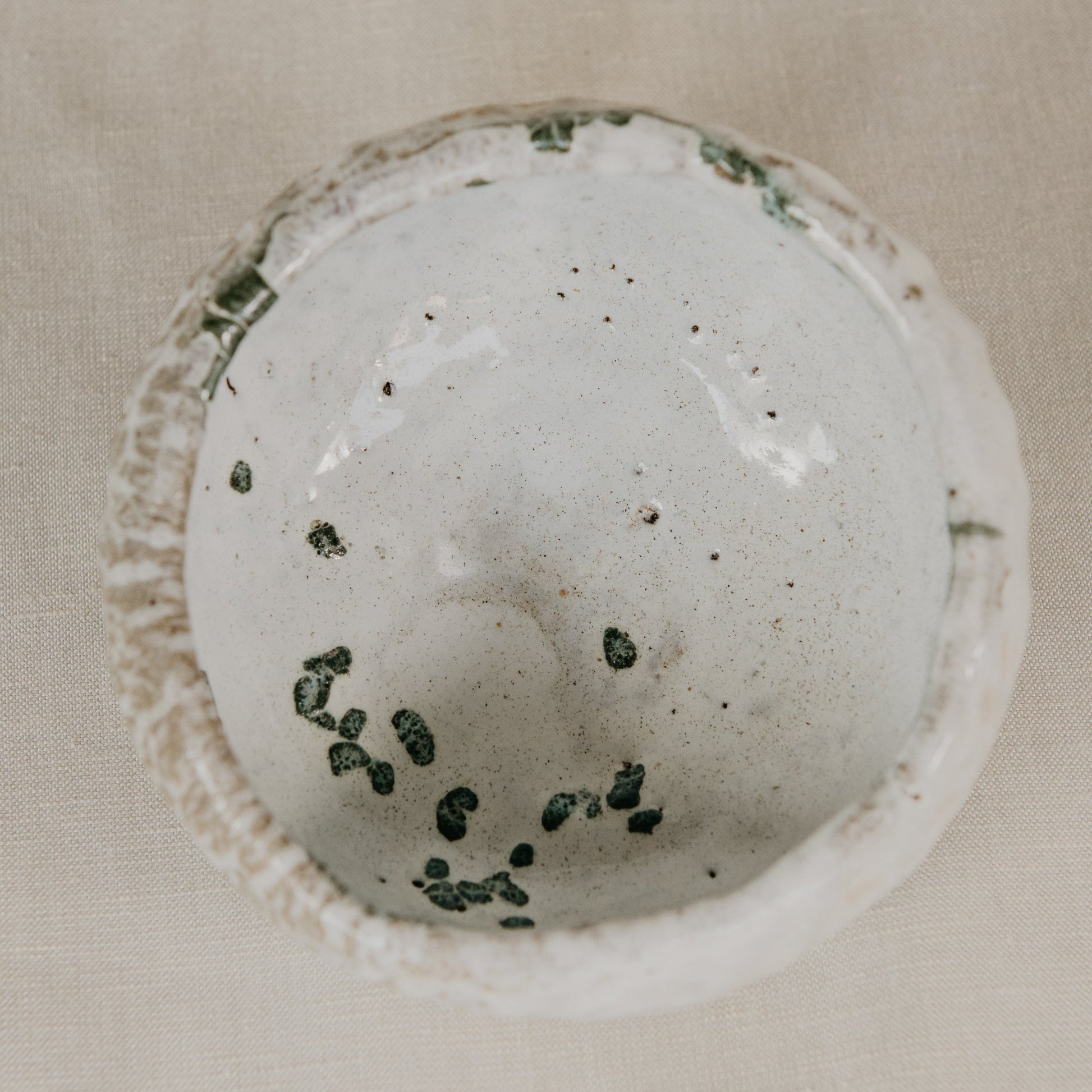 White bath bomb with green specks on a beige background