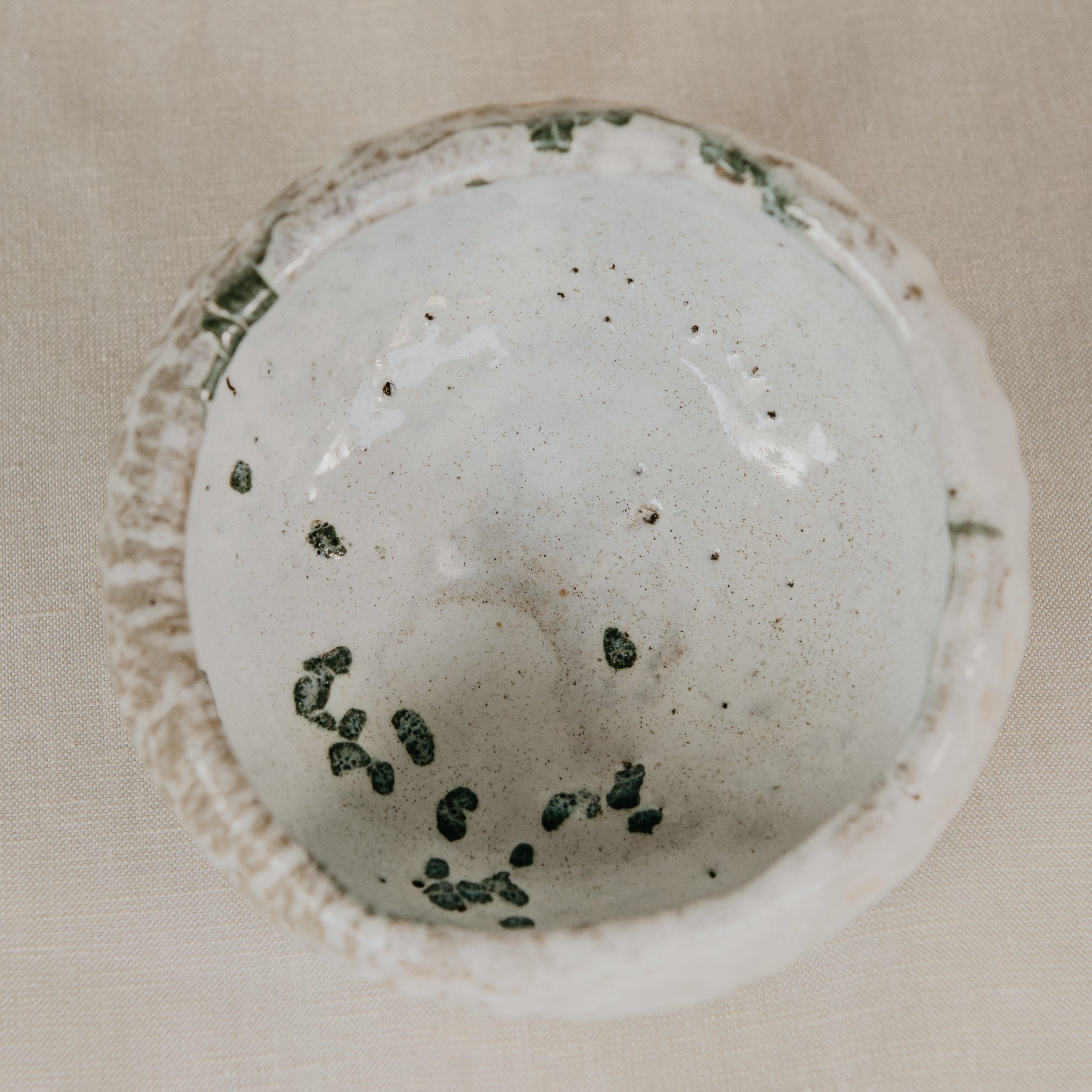 White bath bomb with green specks on a beige background