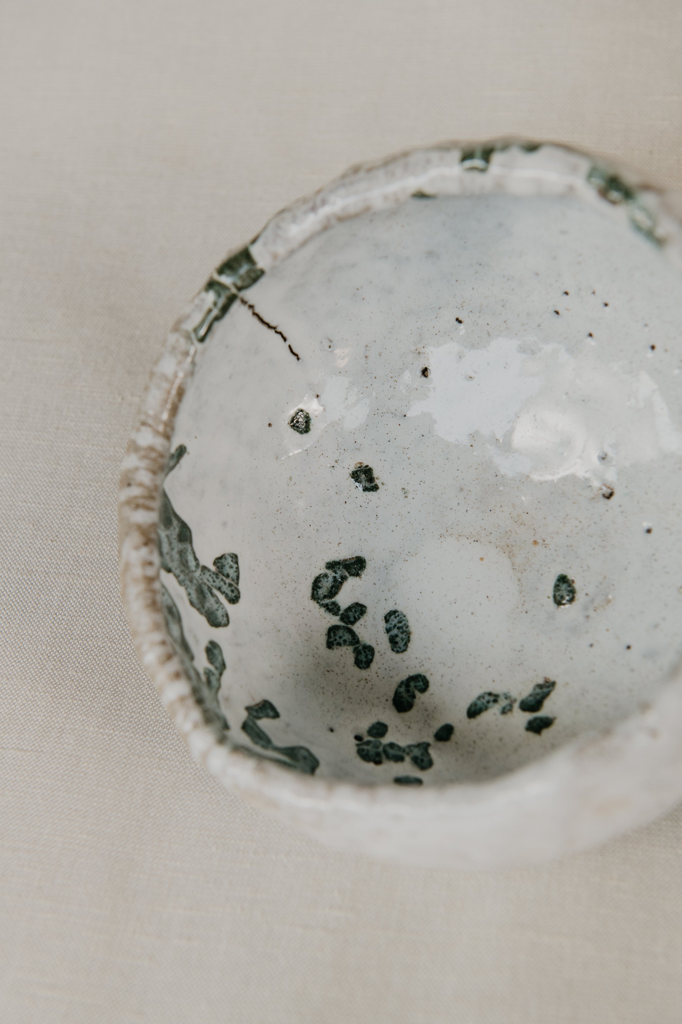 Close-up of a textured ceramic bowl with speckled pattern on a light background