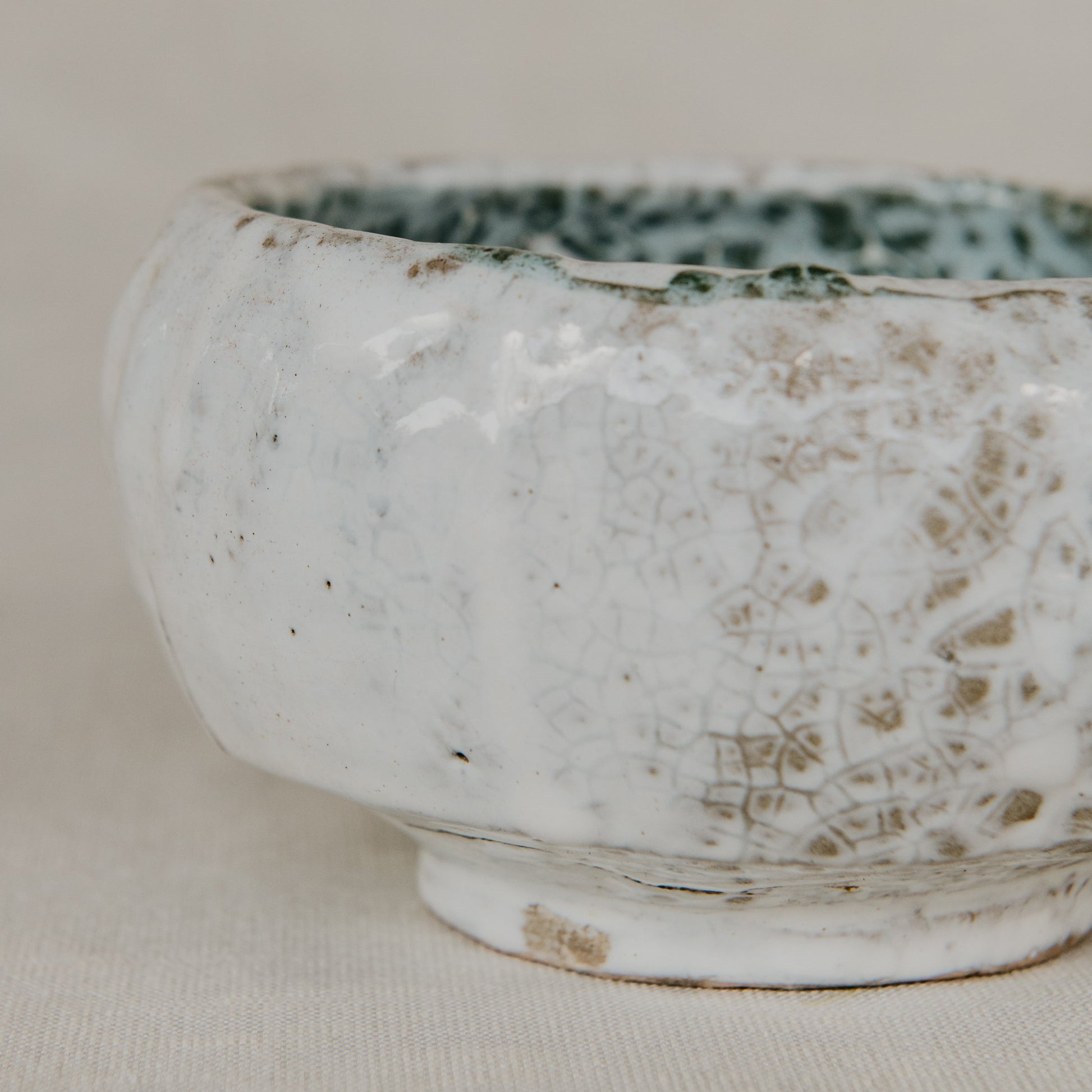 White ceramic bowl with speckled pattern on a beige background