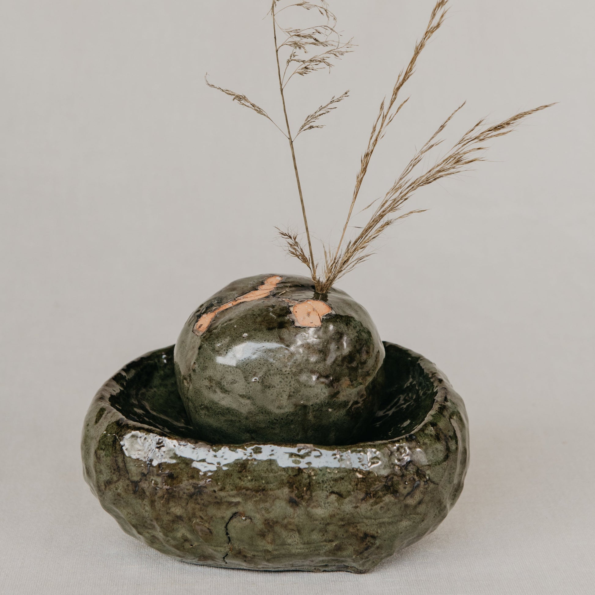 Two ceramic bowls with a small plant on a light gray background