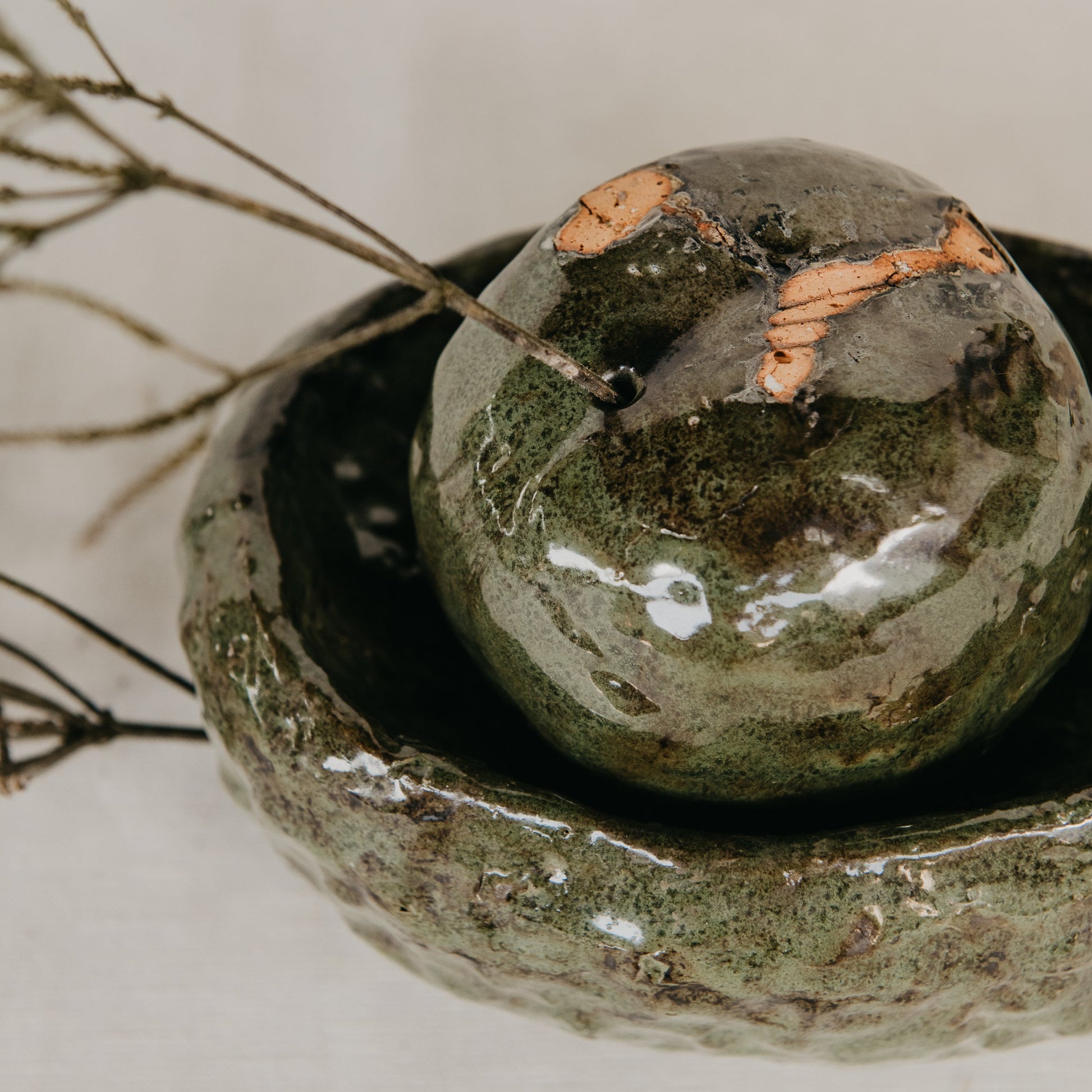 Ceramic bowl with a spherical green object on a neutral background