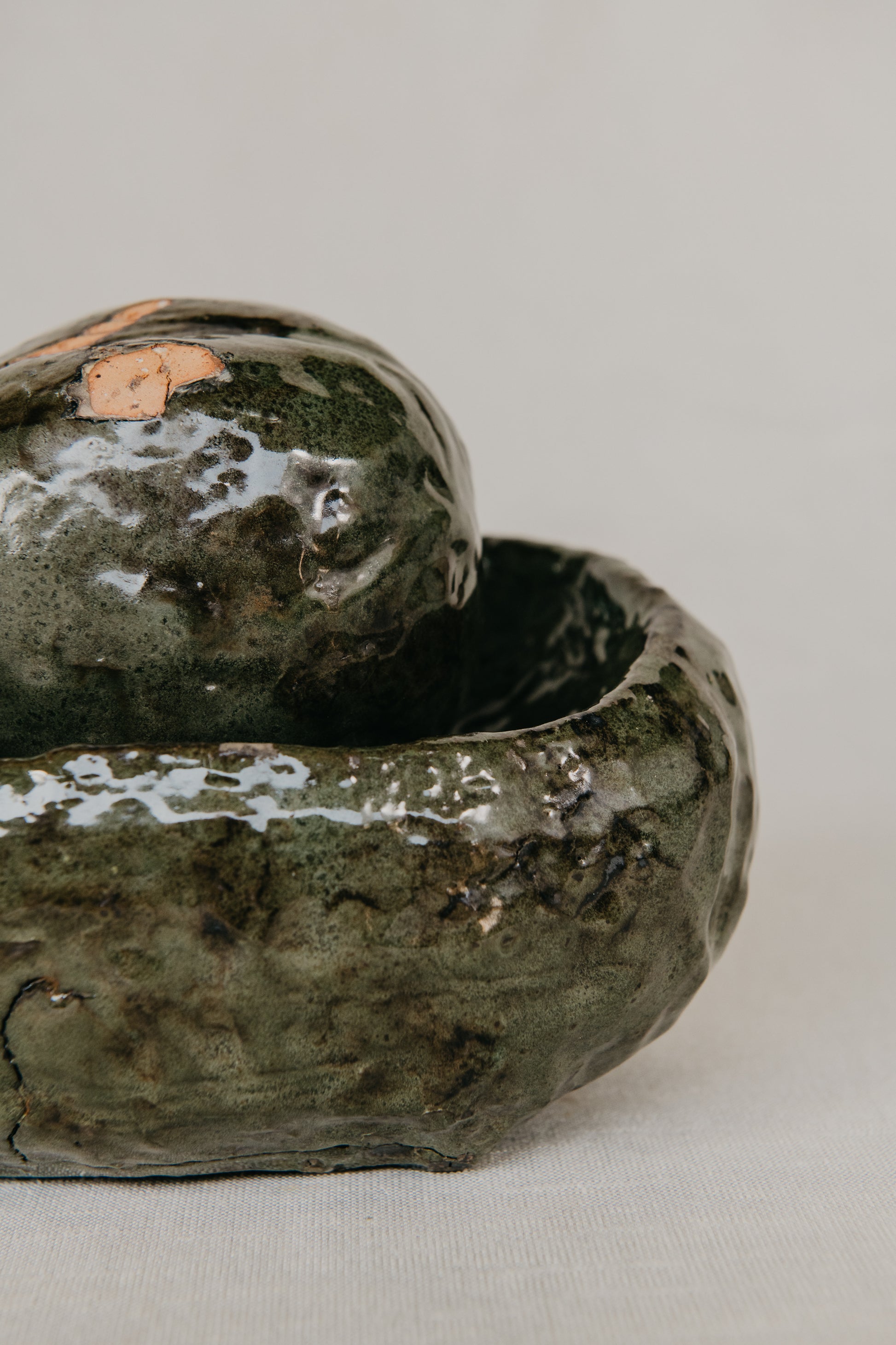 Green ceramic bowl with a lid on a light gray background