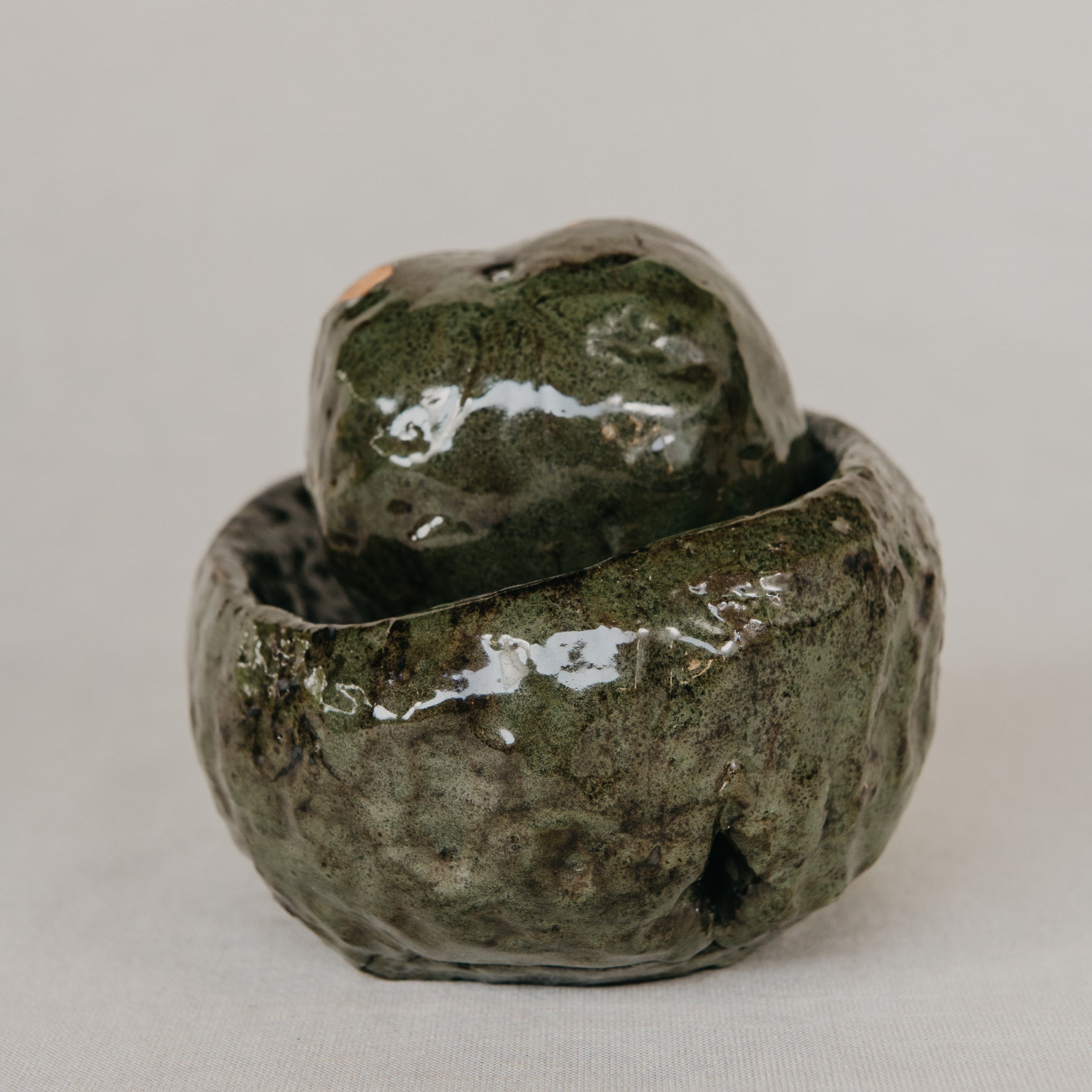 Green ceramic bowl with lid on a light gray background