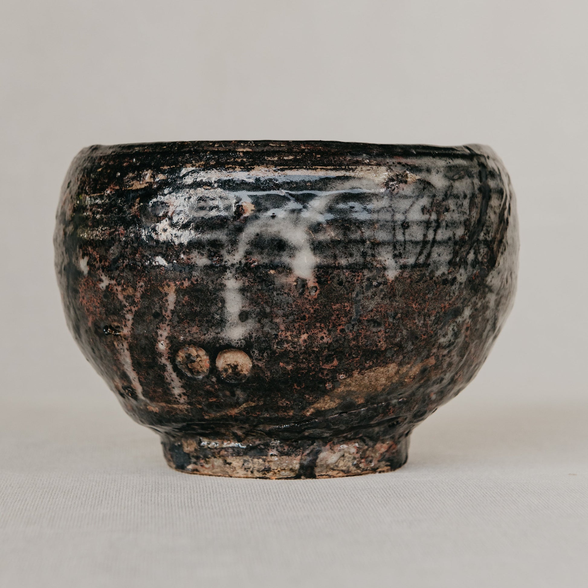 Black ceramic bowl with textured surface on a light gray background