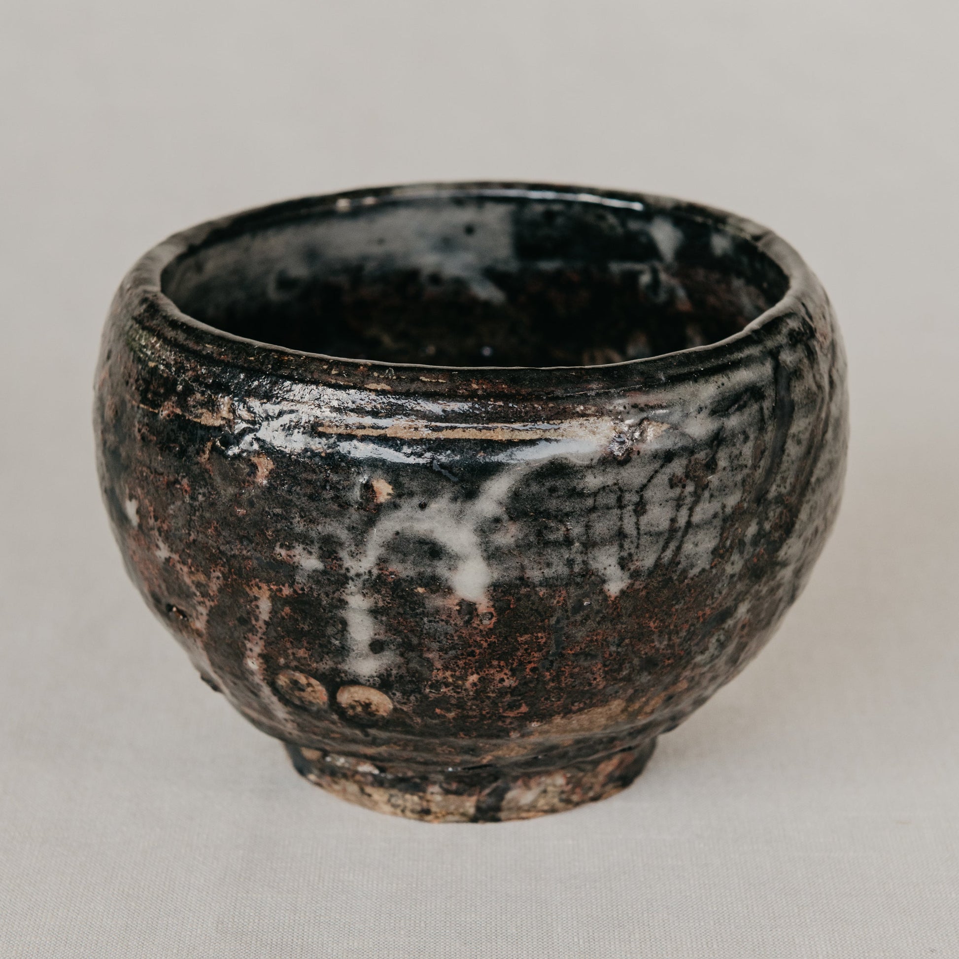 Black ceramic cup with a textured surface on a light gray background