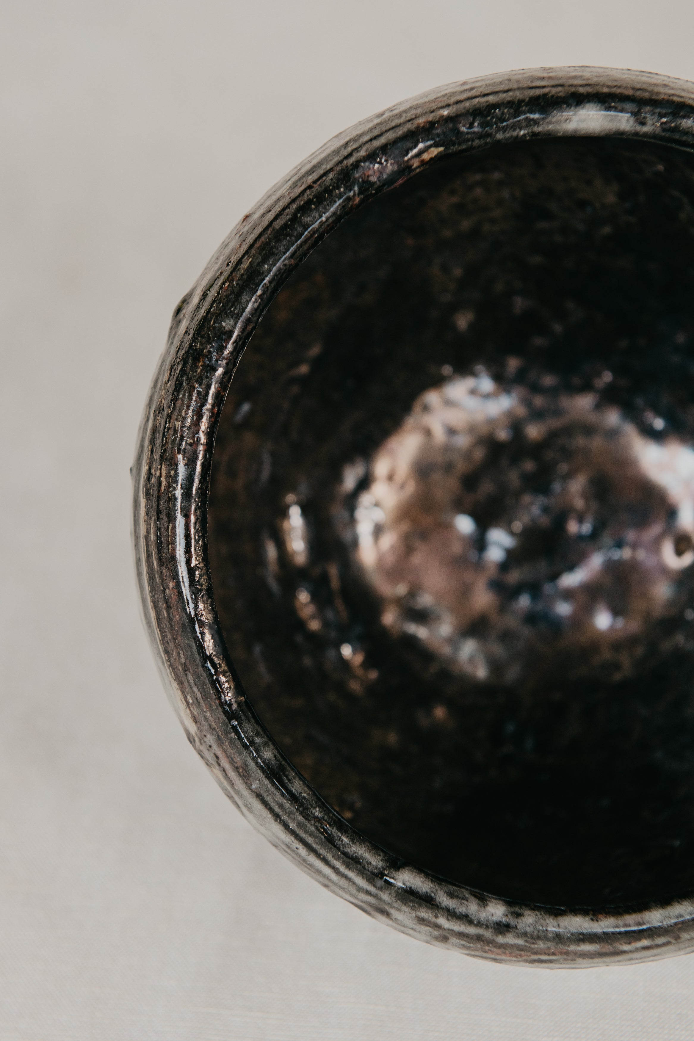 Close-up of a dark ceramic bowl with a textured interior on a light background