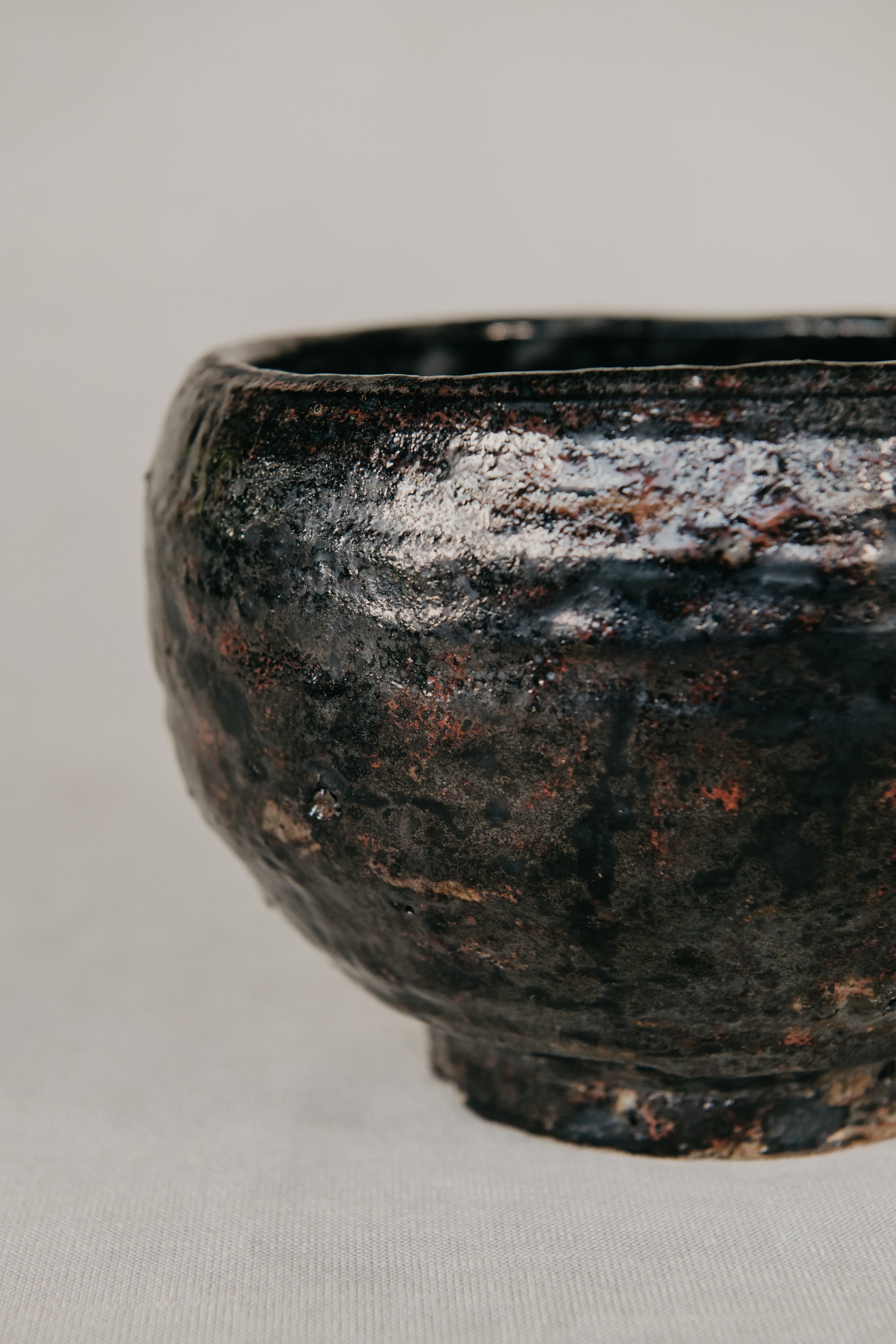 Black ceramic bowl with a textured surface on a light gray background