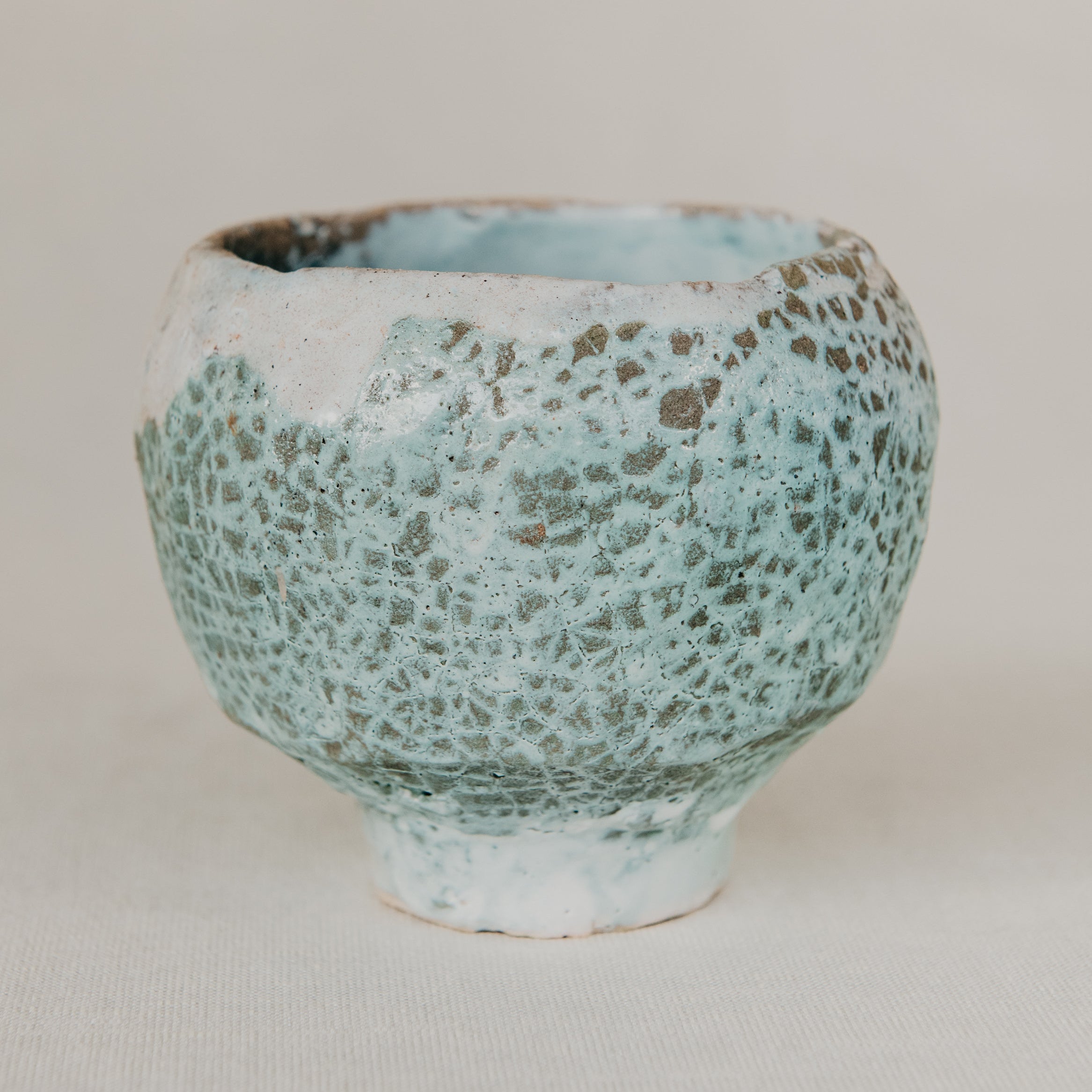 Ceramic cup with textured surface on a plain background