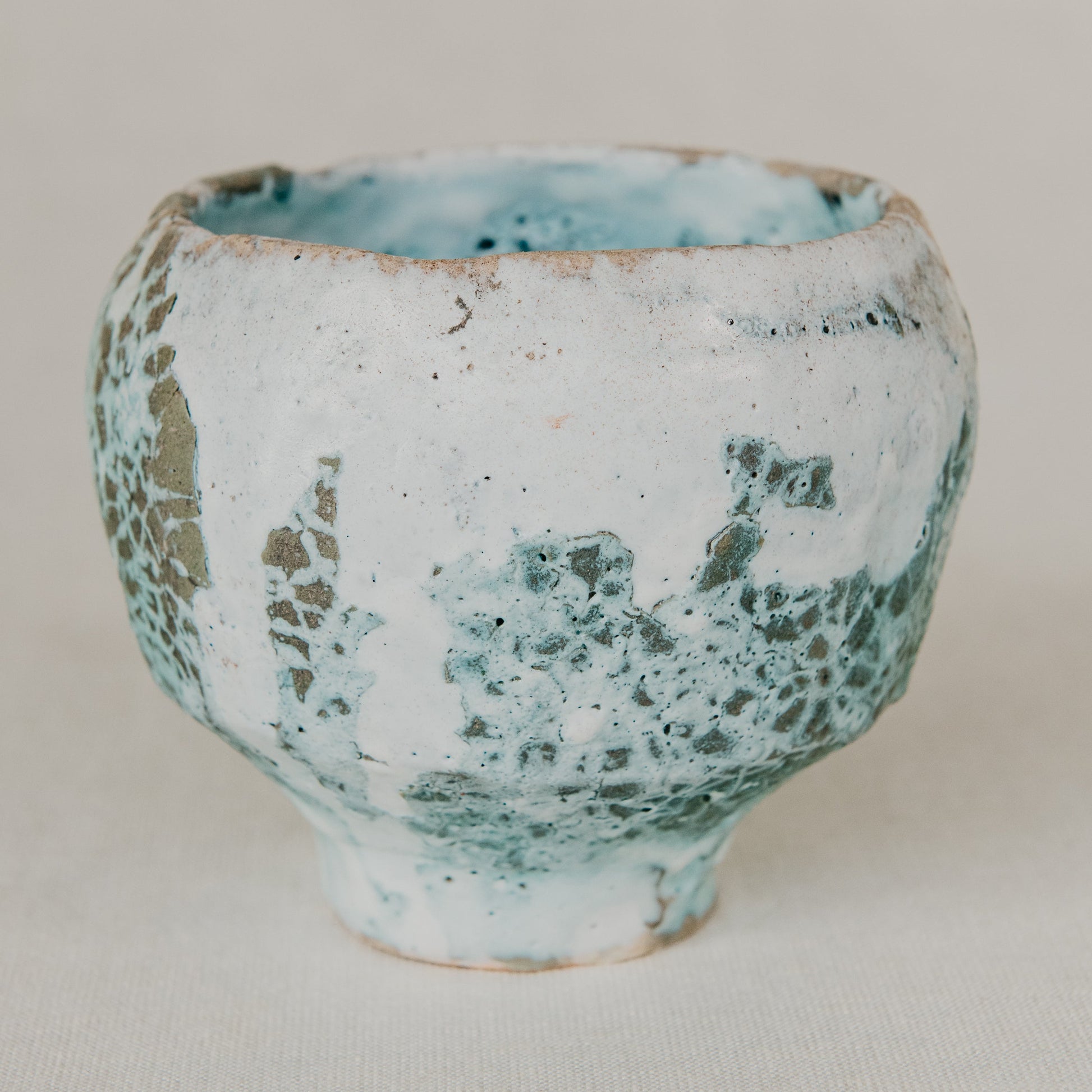 Small ceramic cup with textured surface on a plain background