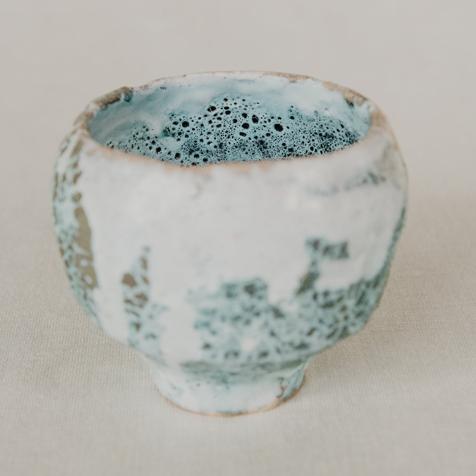 Ceramic cup with blue and white speckled design on a beige background