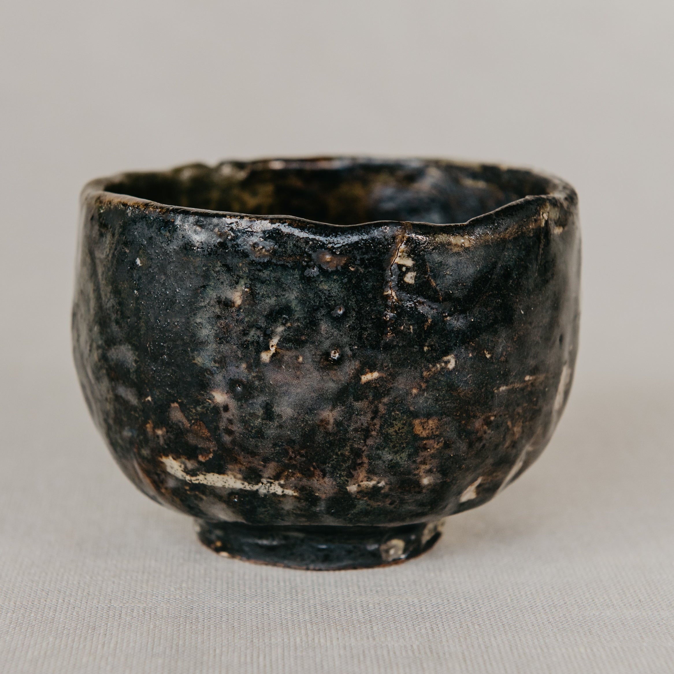 Black ceramic cup with a textured surface on a light gray background