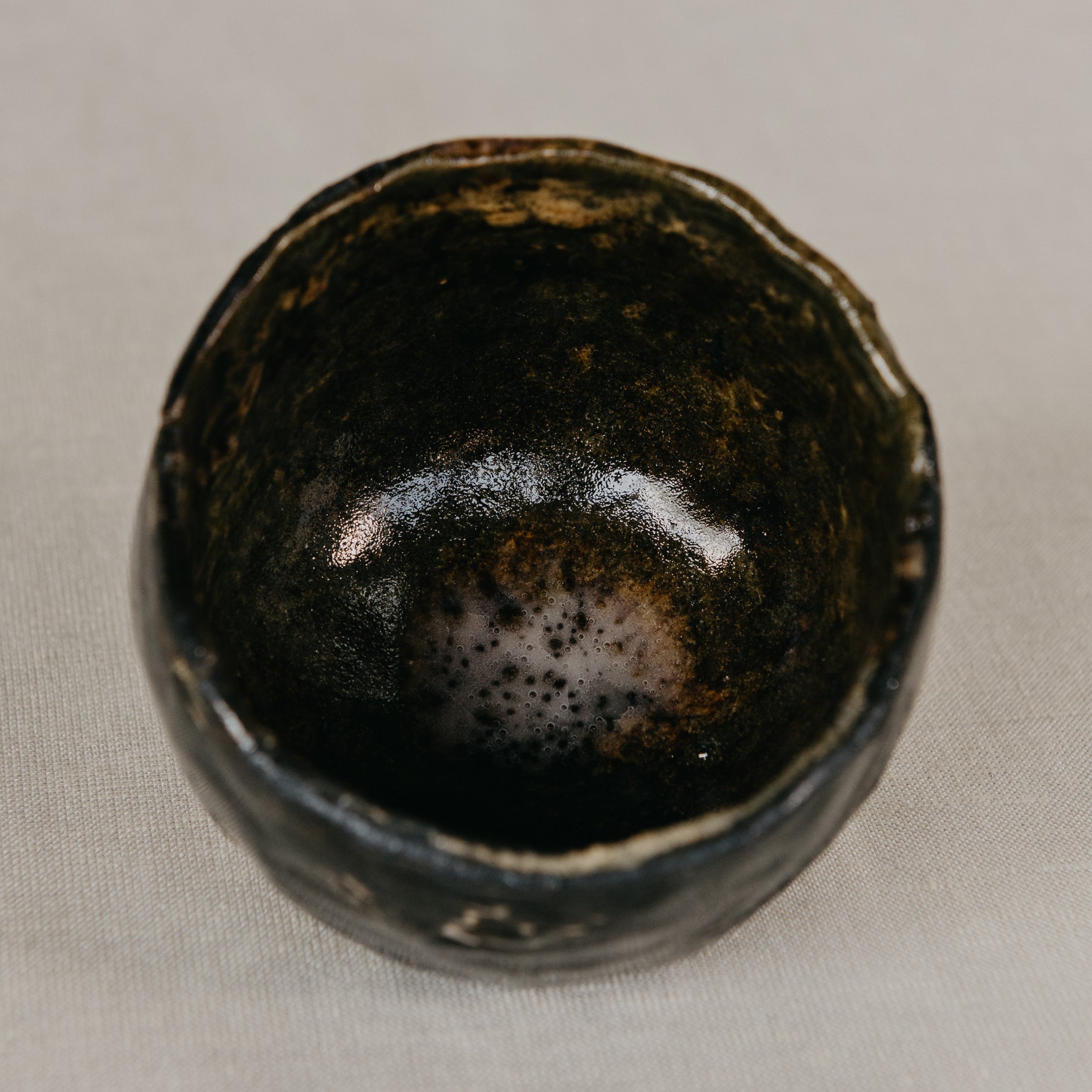 Black ceramic cup with speckled texture on a beige background