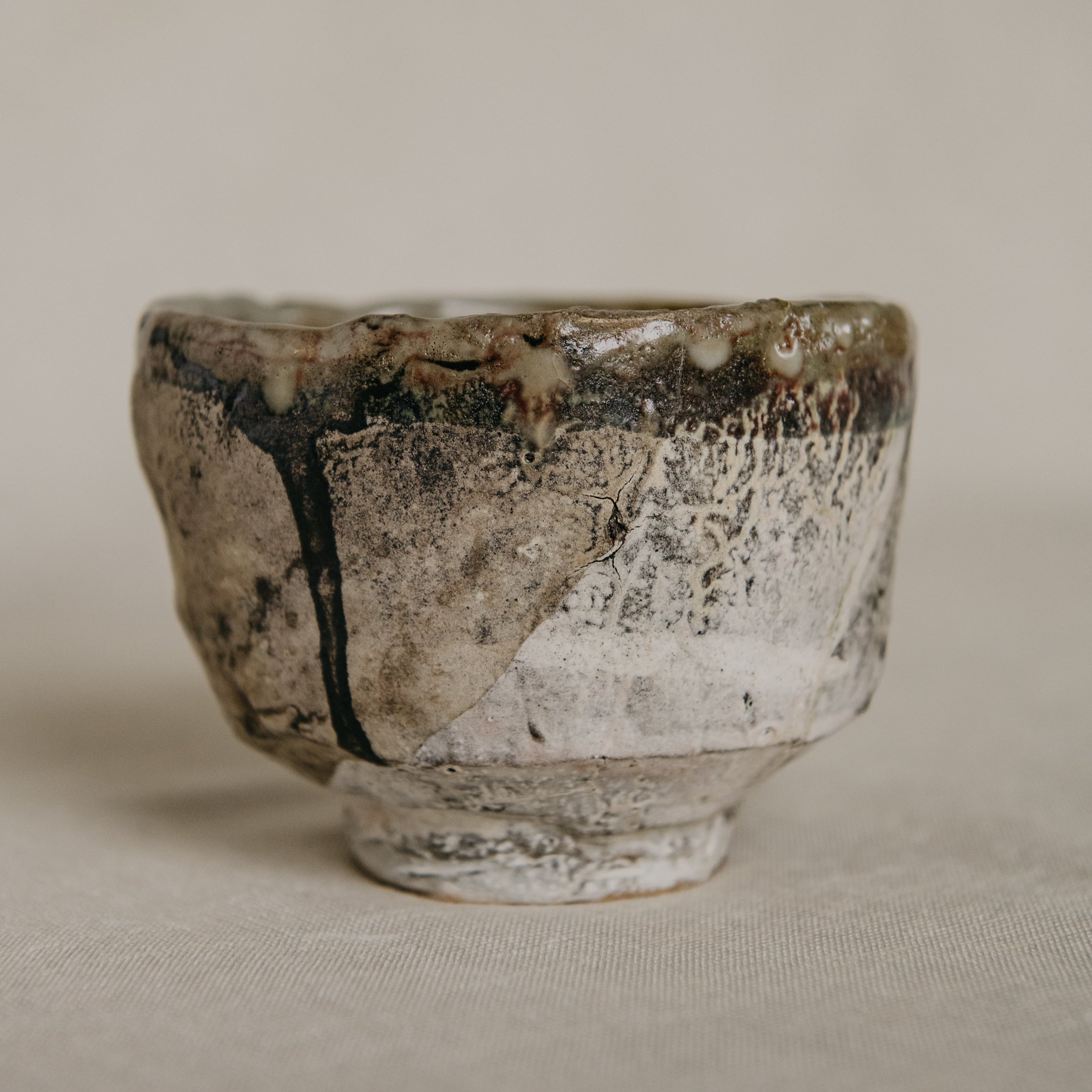 Small ceramic cup with a textured surface on a beige background