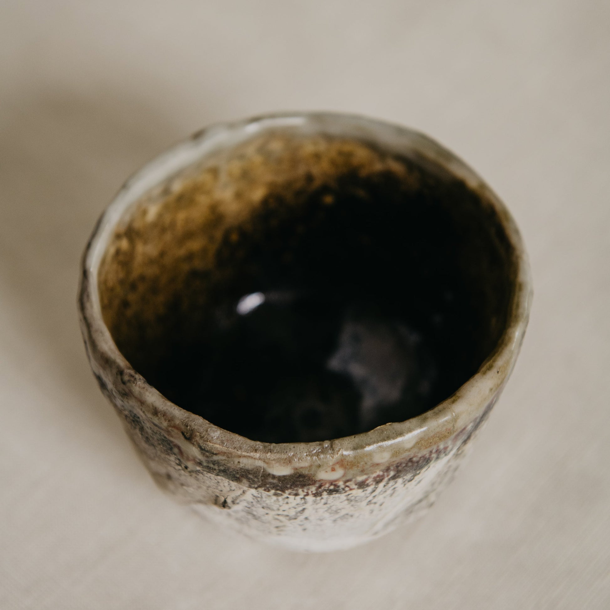Ceramic cup with textured exterior on a beige surface