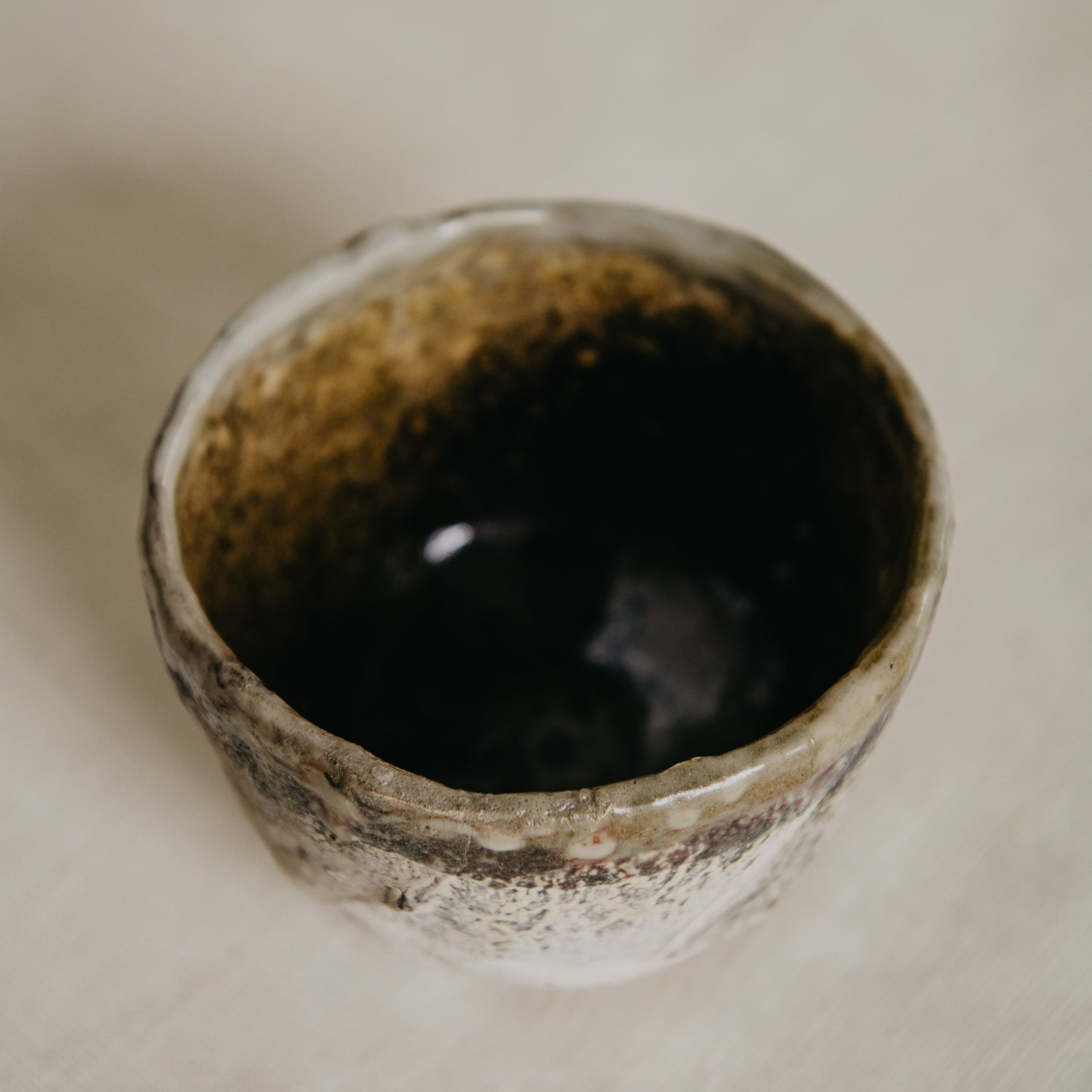 Ceramic cup with textured exterior on a beige surface