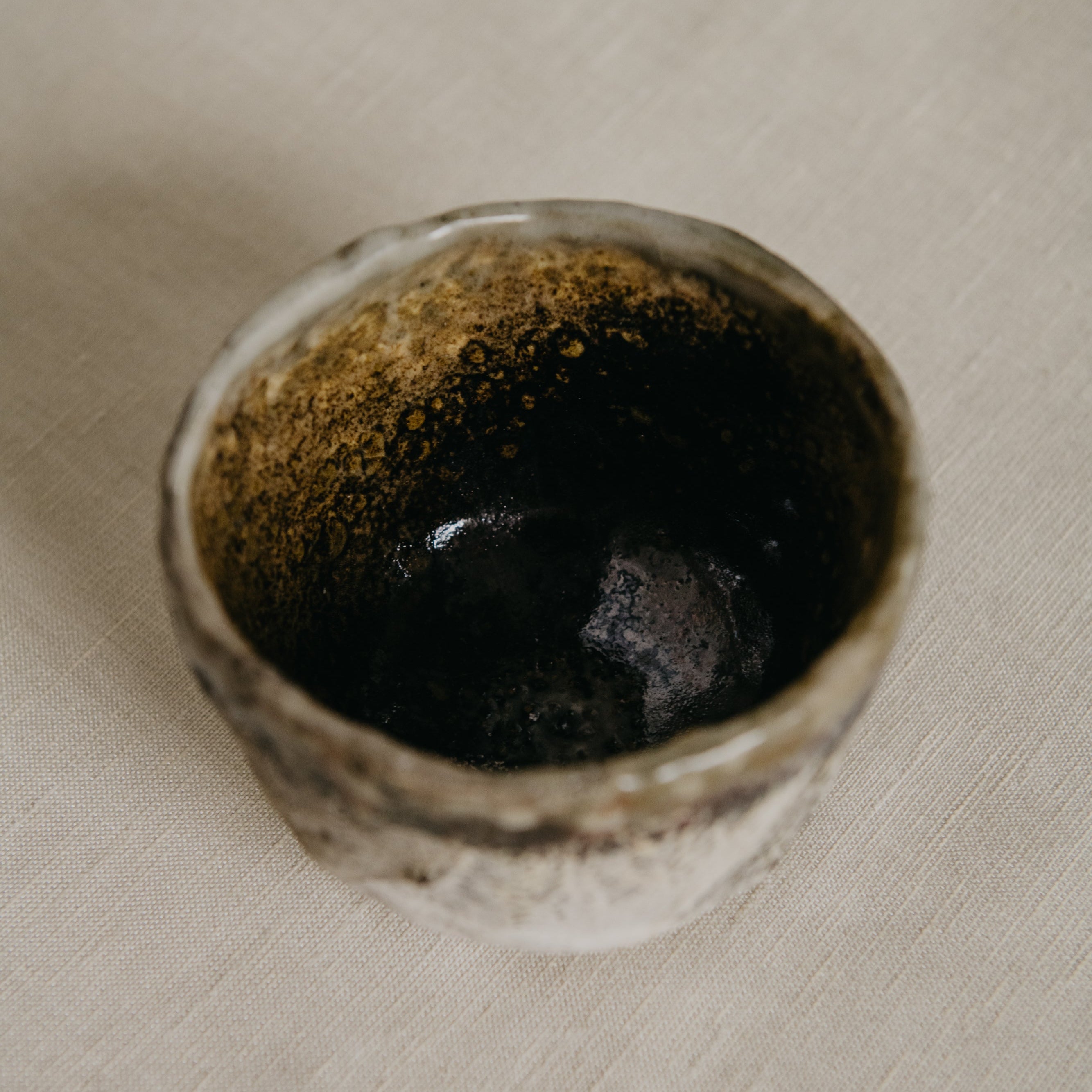 Small ceramic bowl with a textured surface on a beige fabric background