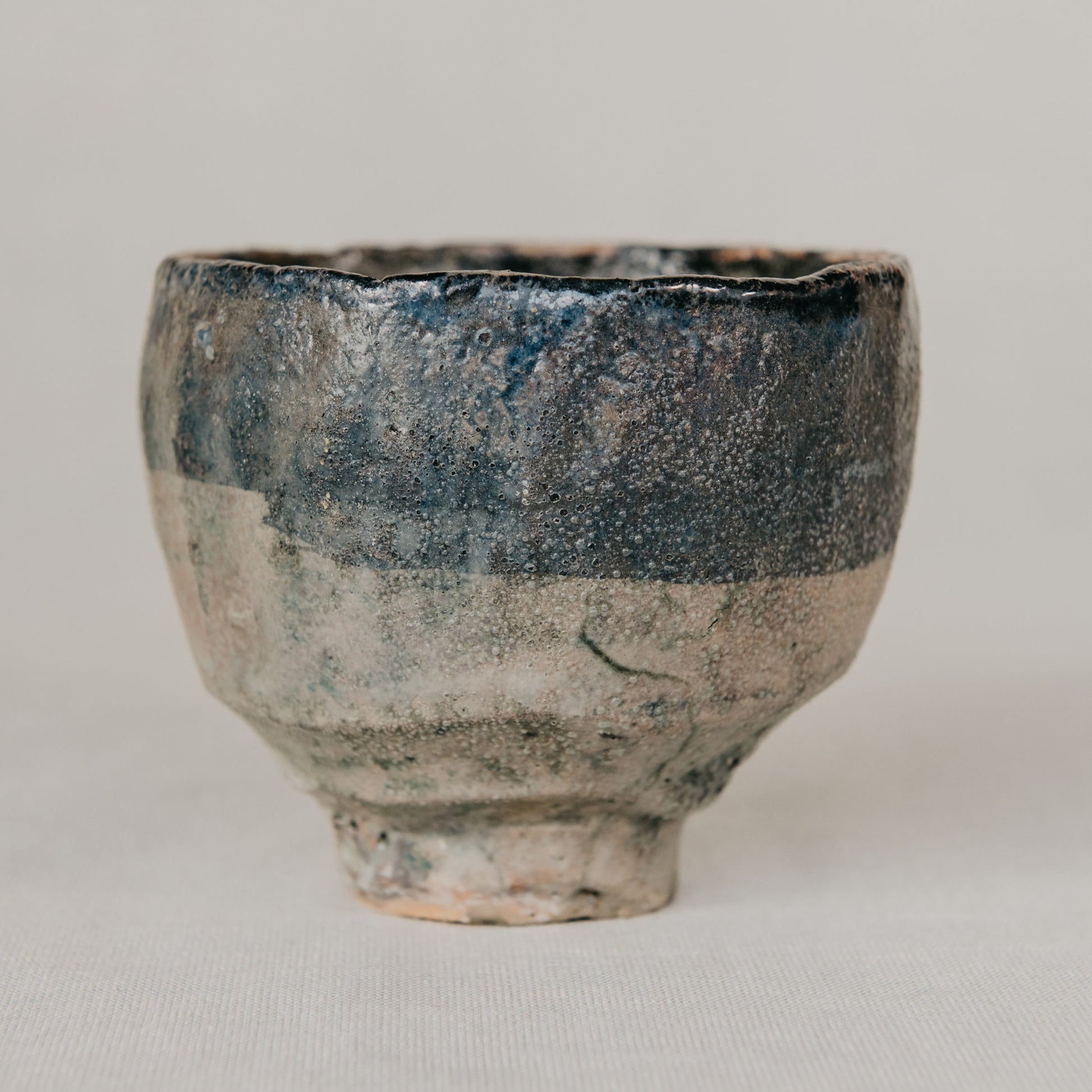 Ceramic cup with blue and gray glaze on a light gray background