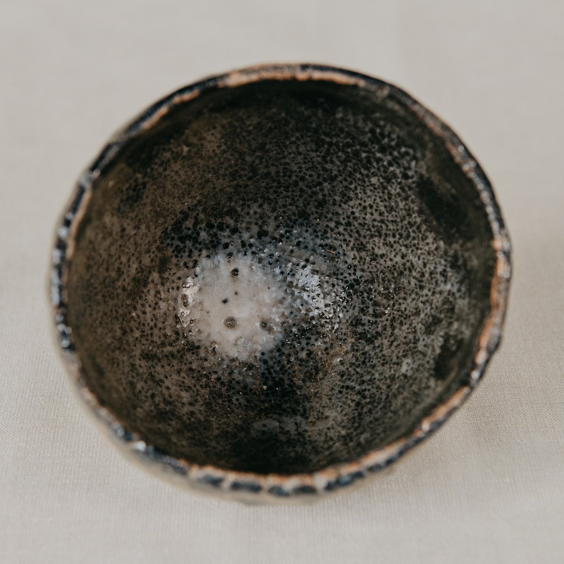 Black ceramic bowl with speckled texture on a light gray background