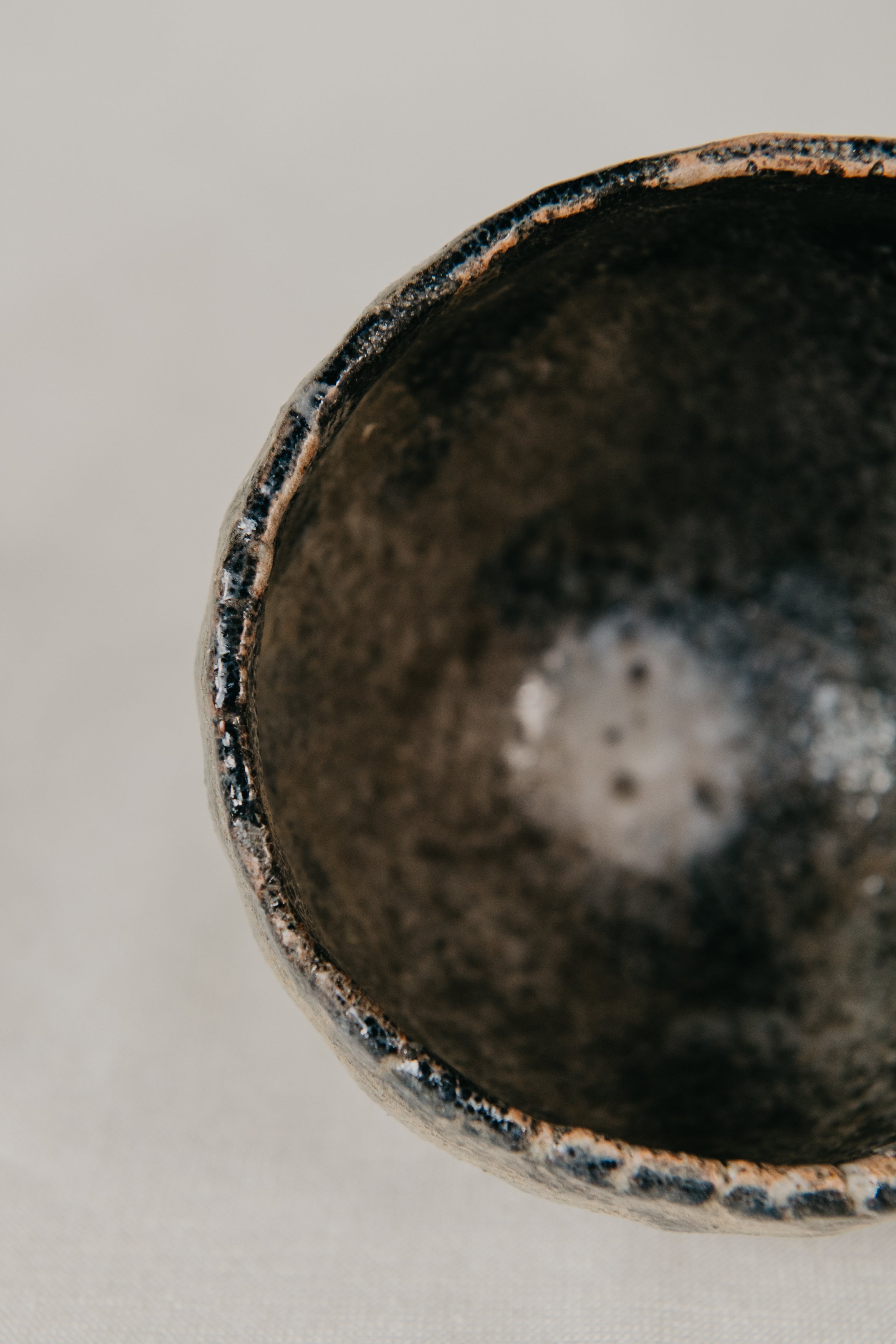 Close-up of a dark ceramic bowl with a textured surface on a light background