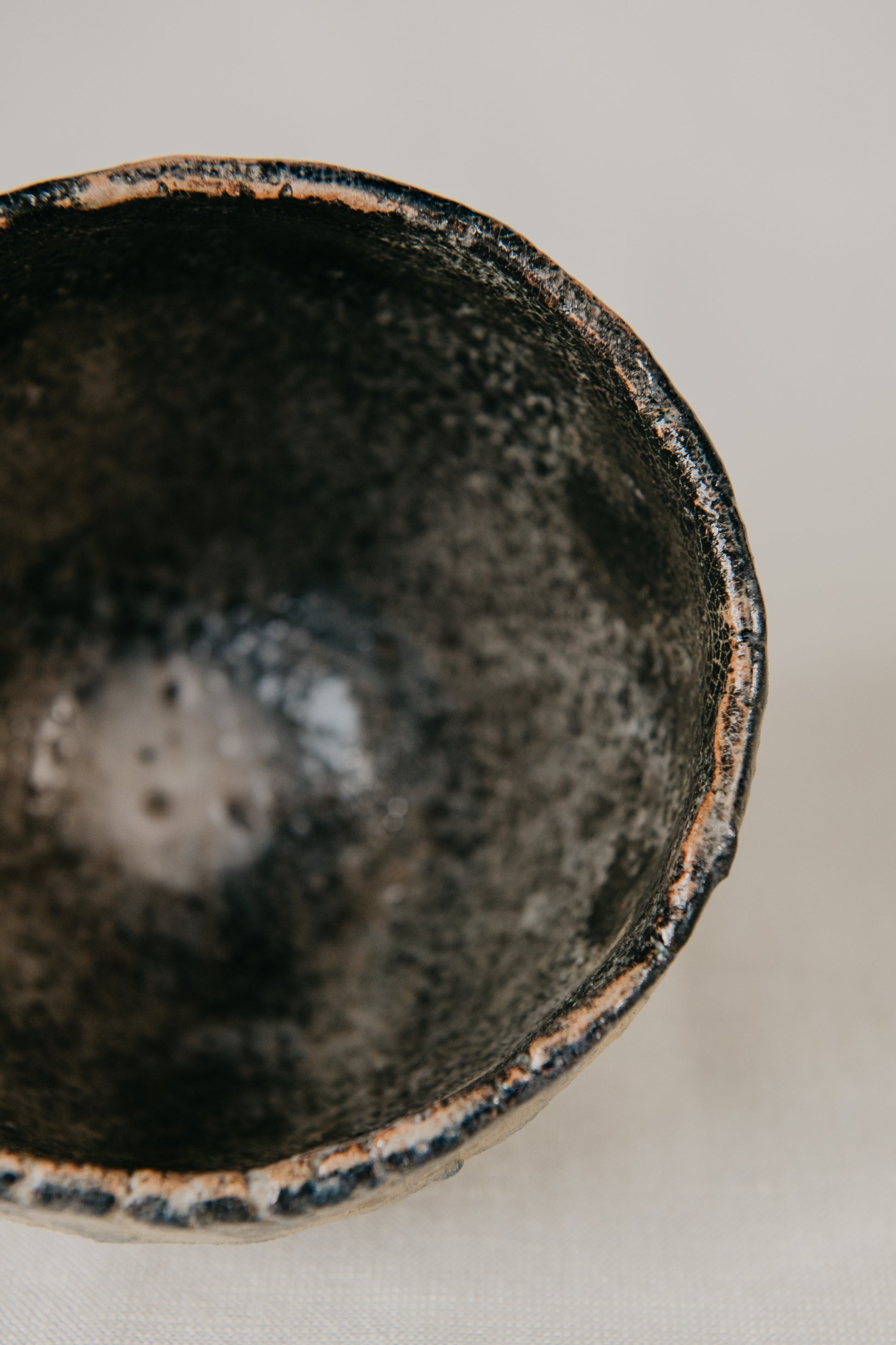 Close-up of a black ceramic bowl with a textured surface on a light background