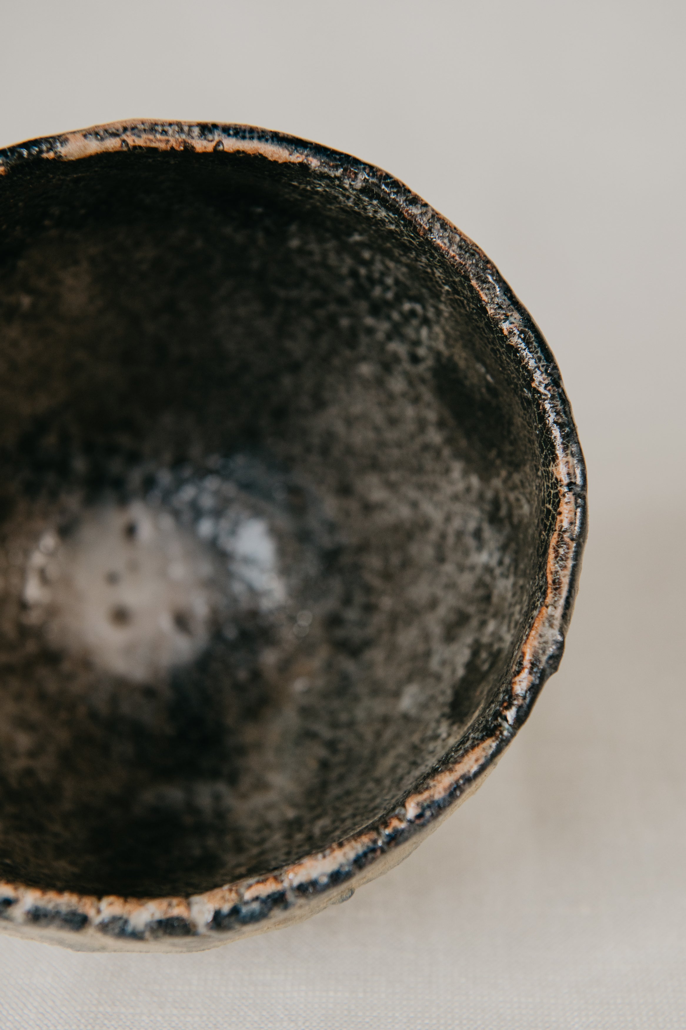 Close-up of a black ceramic bowl with a textured surface on a light background