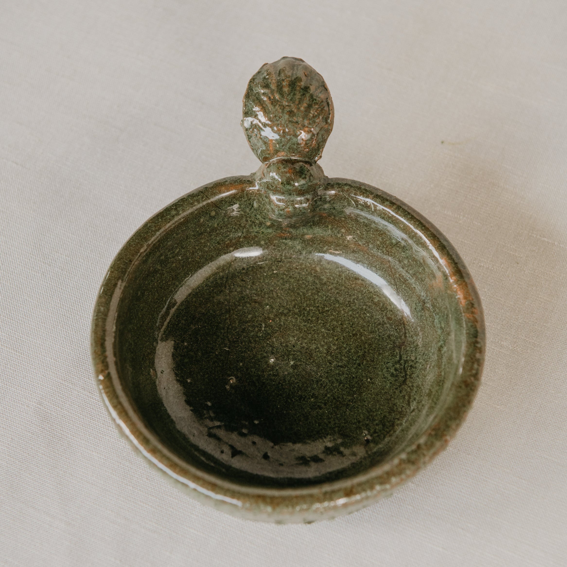 Green ceramic dish with a lid on a light gray background