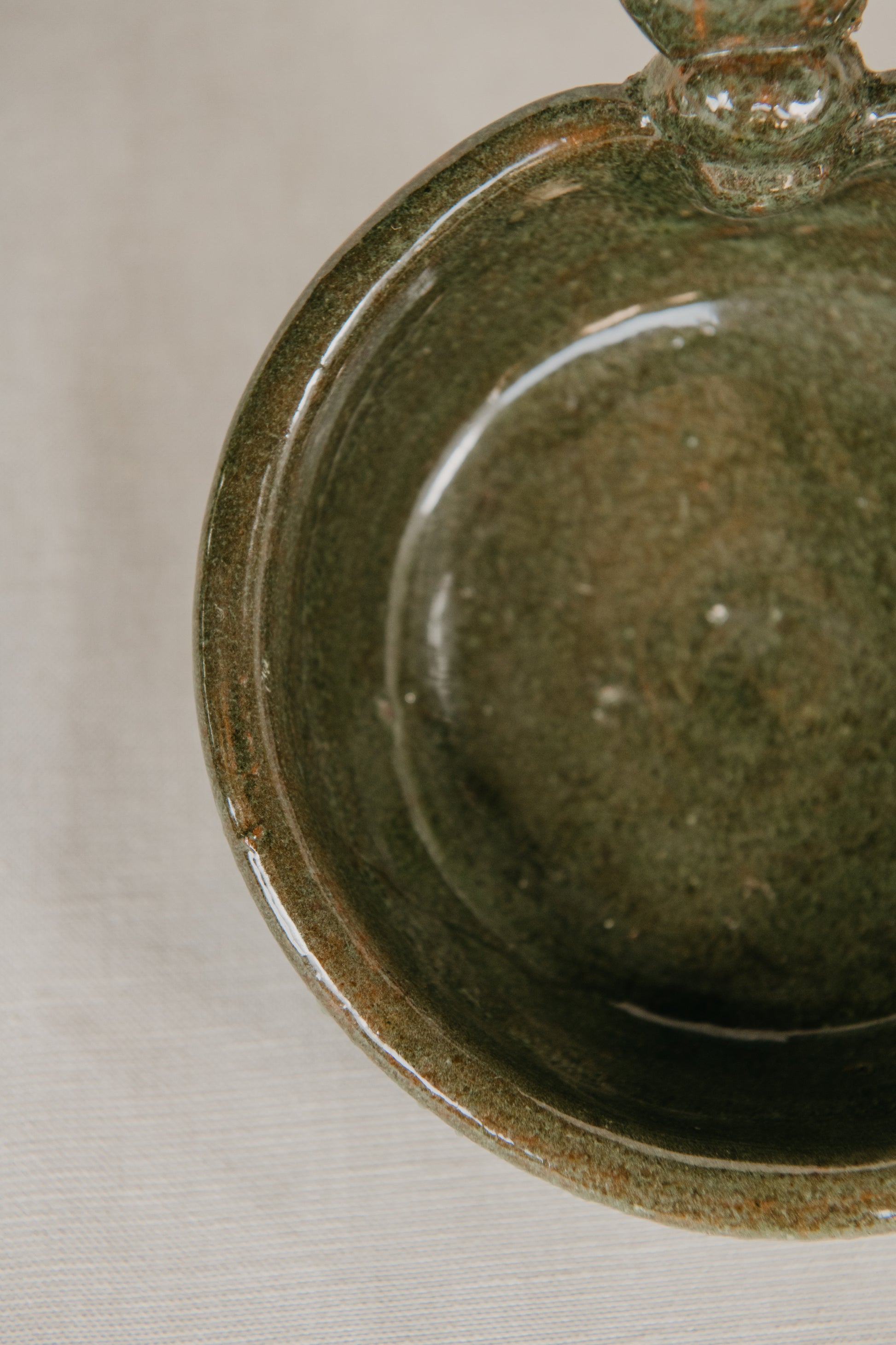 Close-up of a green ceramic bowl on a neutral background
