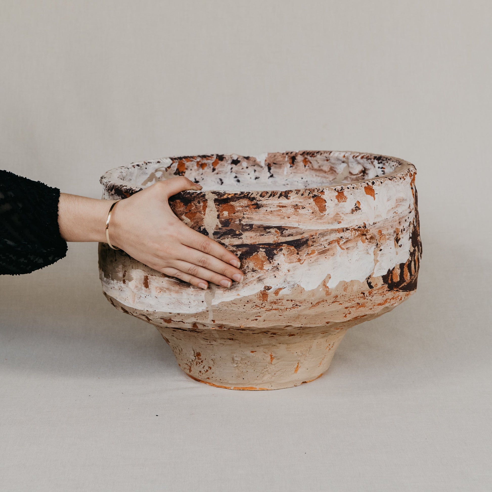 Hand holding a large ceramic bowl against a plain background