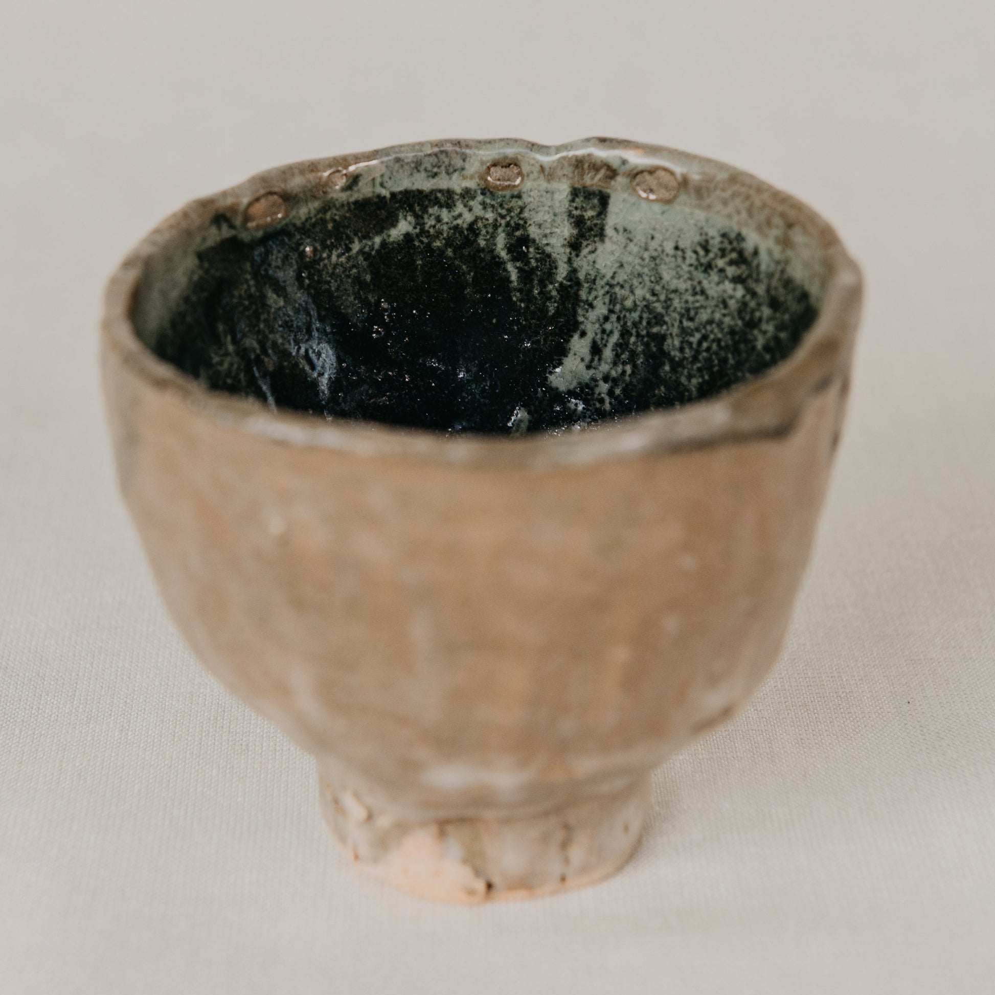 Small ceramic cup with a textured surface on a plain background