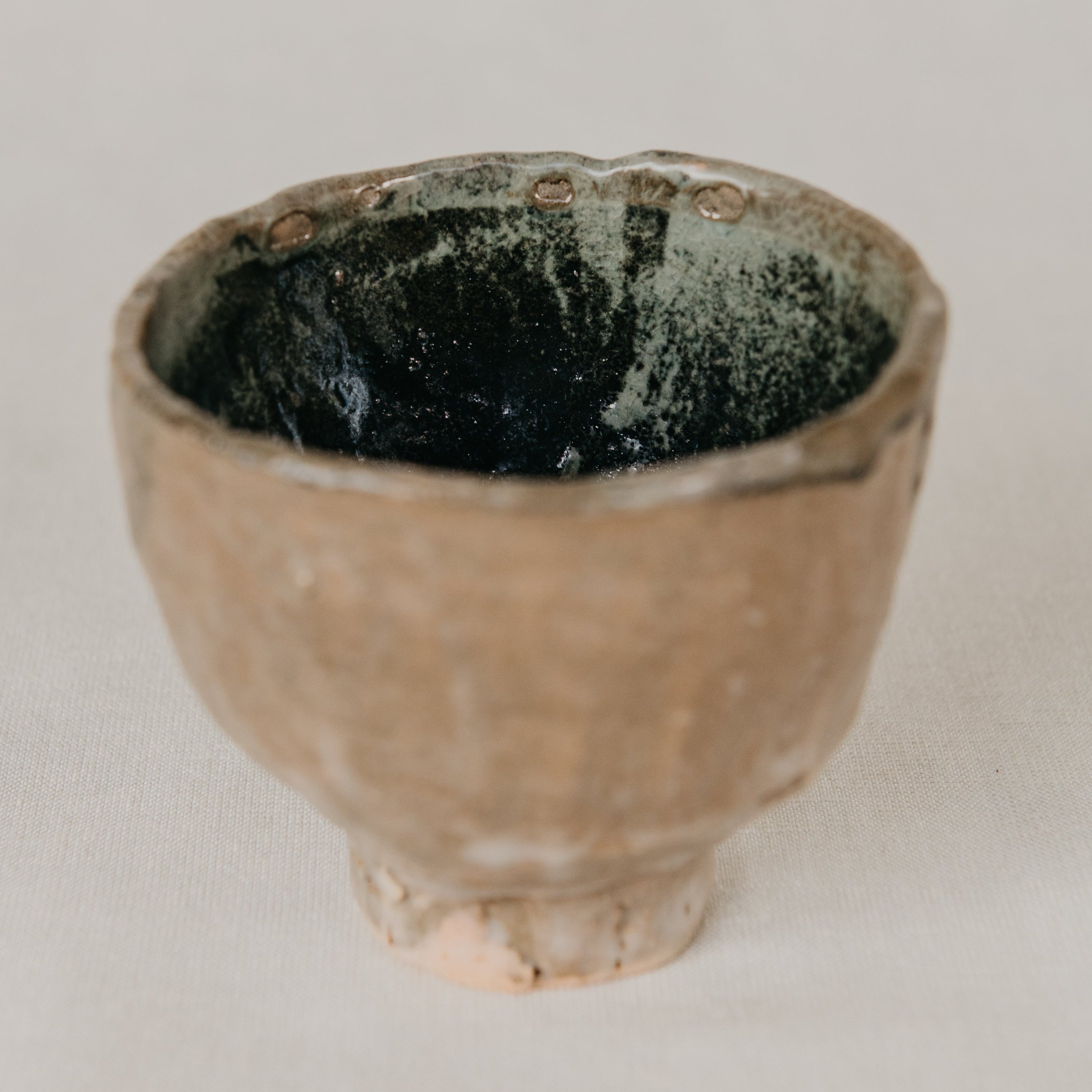 Small ceramic cup with a textured surface on a plain background