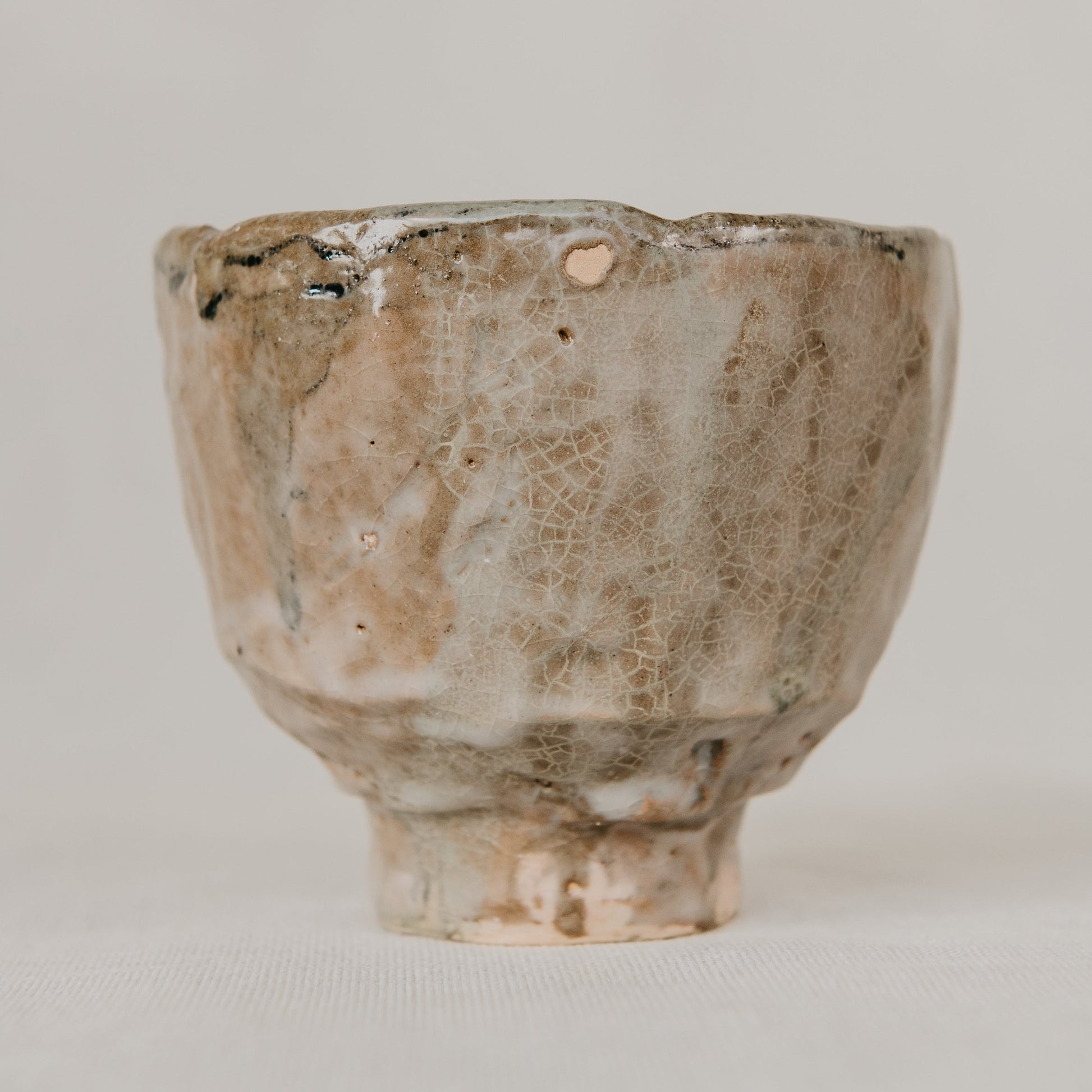 Small ceramic cup with a textured surface on a plain background