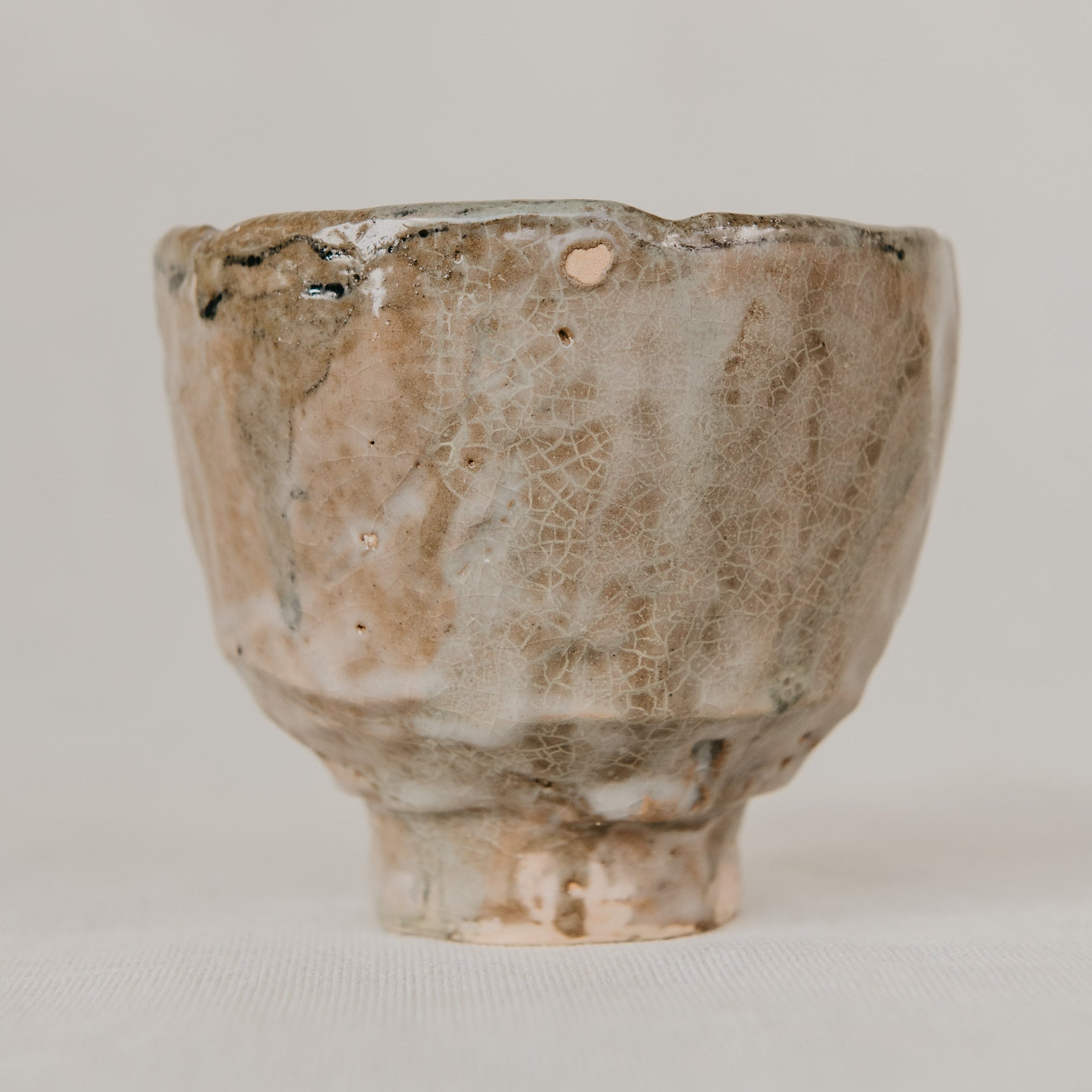 Small ceramic cup with a textured surface on a plain background
