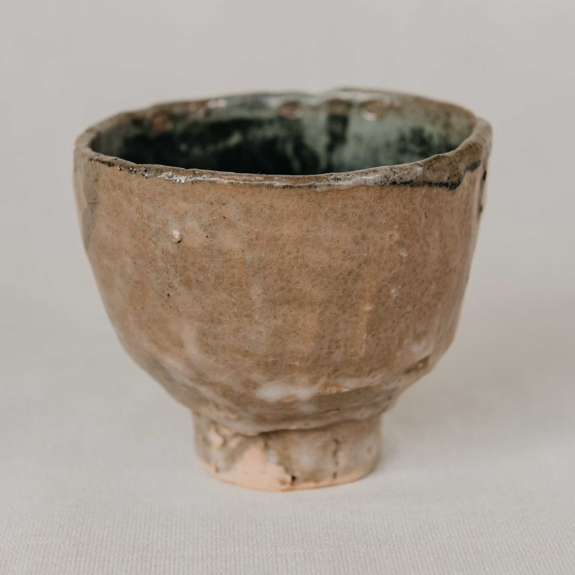 Small ceramic cup with a textured surface on a plain background