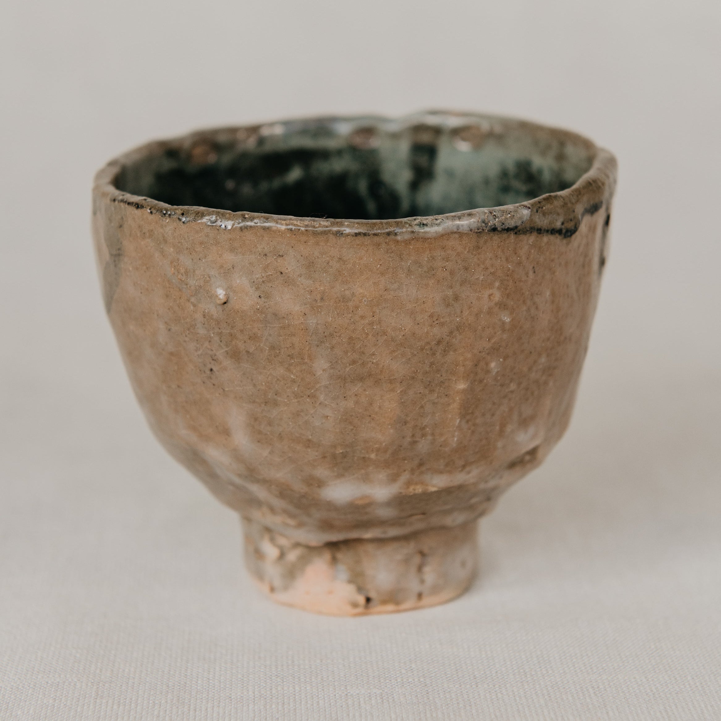 Small ceramic cup with a textured surface on a plain background