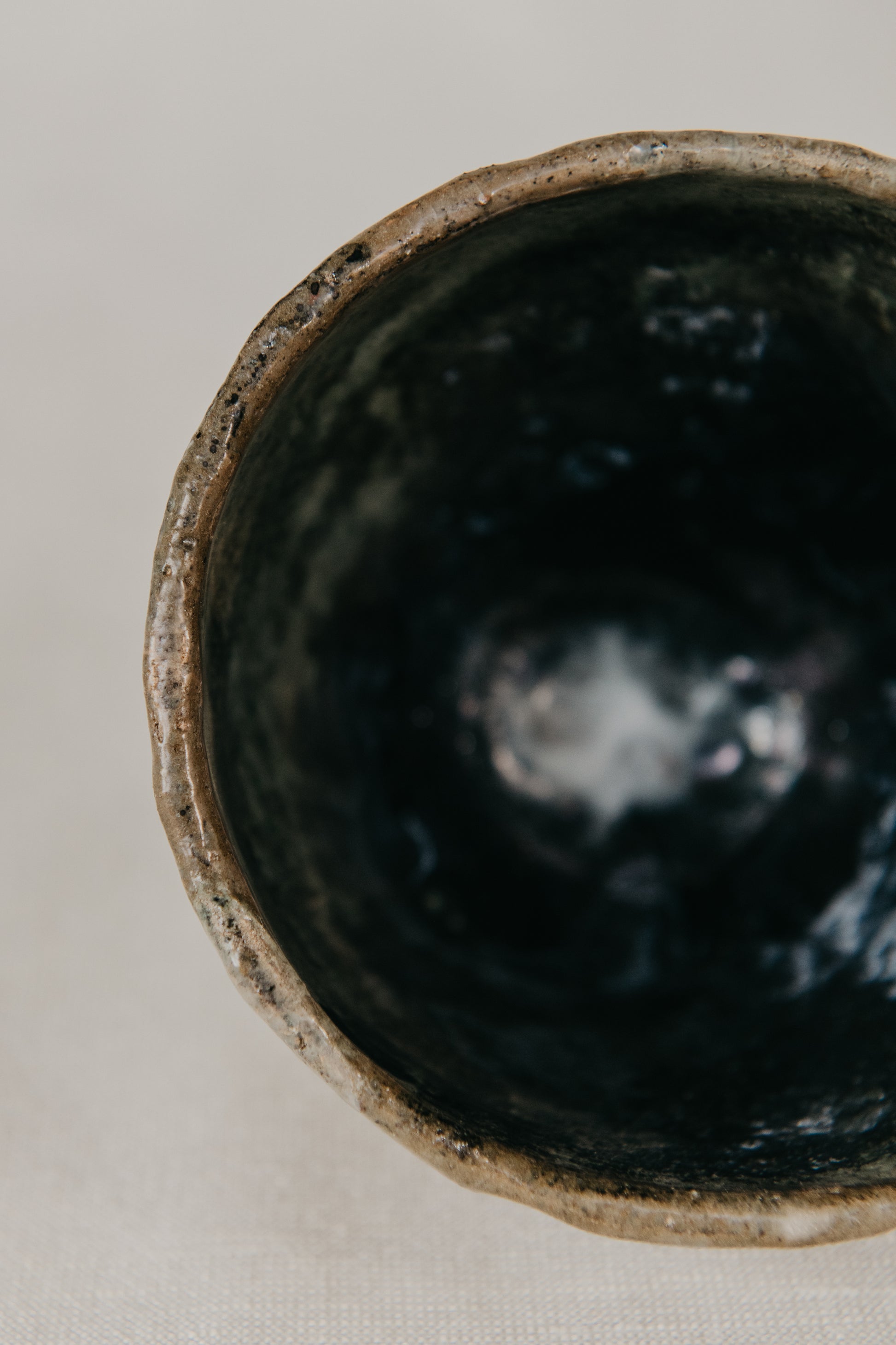 Close-up of a dark ceramic bowl with a textured interior on a light background