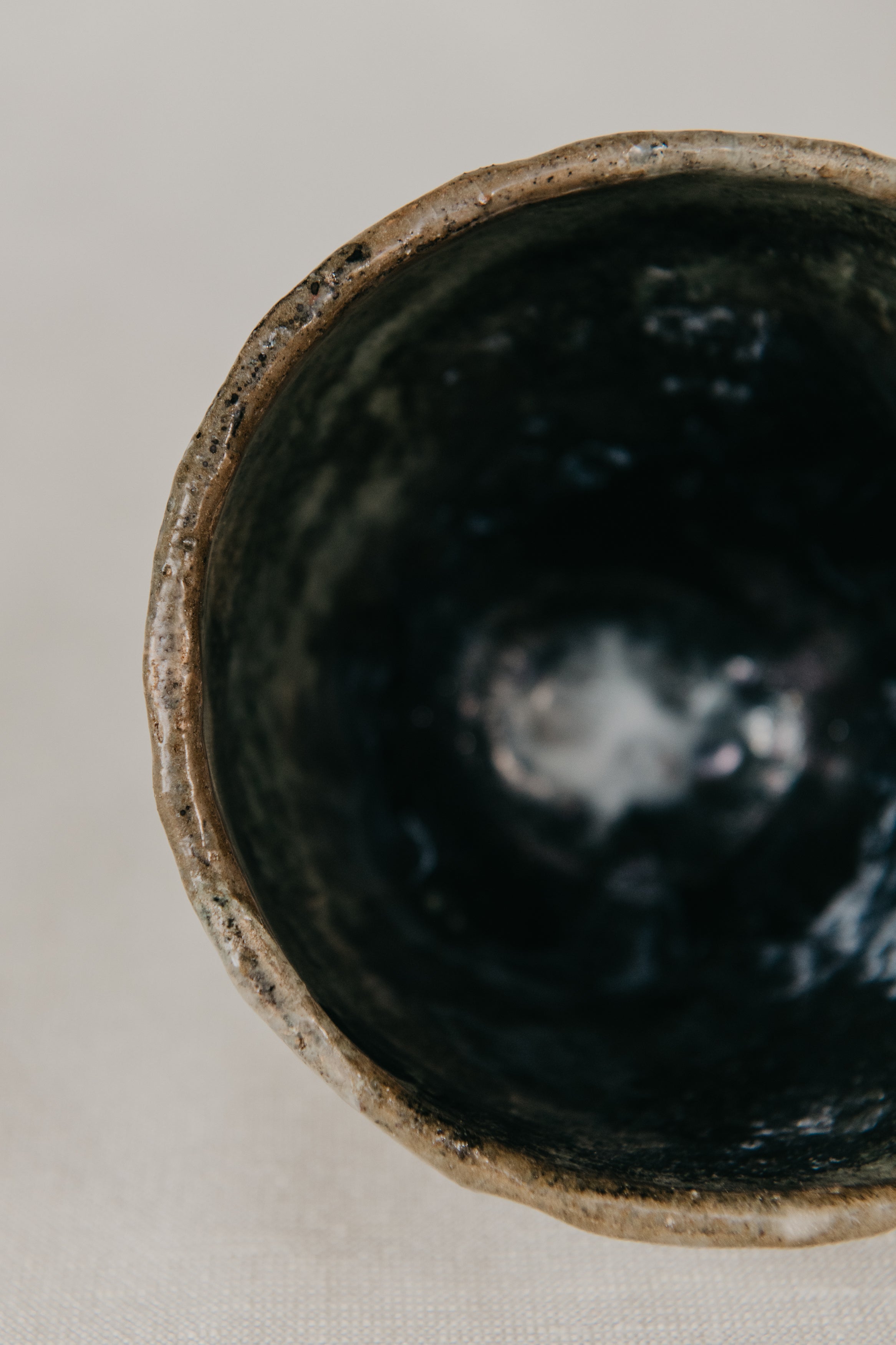 Close-up of a dark ceramic bowl with a textured interior on a light background