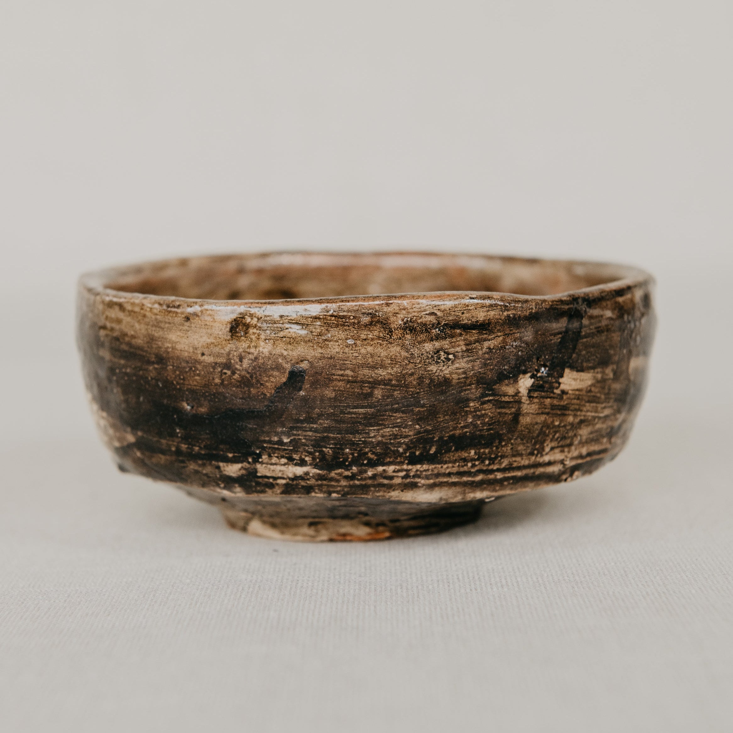 Small brown ceramic bowl on a light gray background