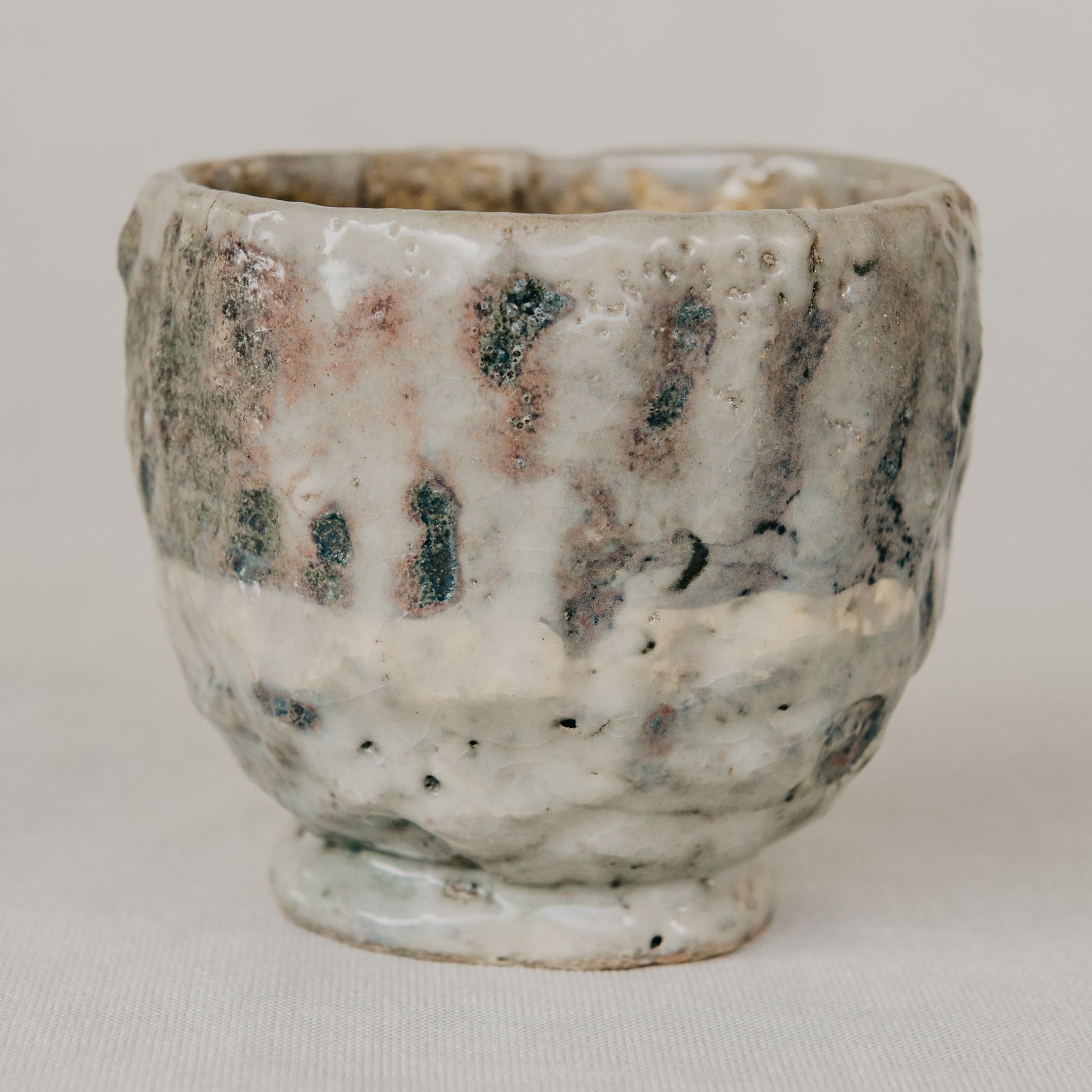 Handmade ceramic cup with textured surface on a plain background