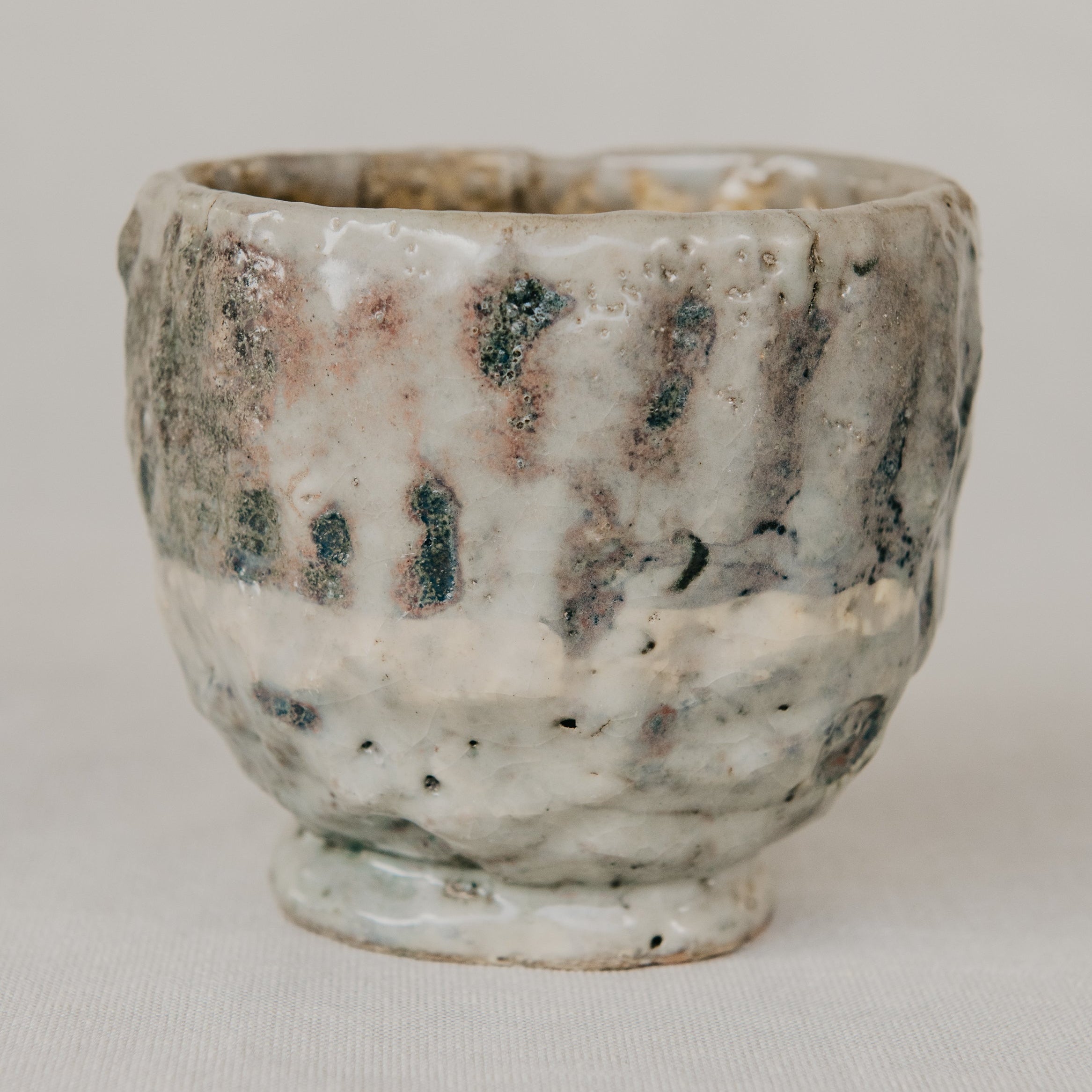 Handmade ceramic cup with textured surface on a plain background