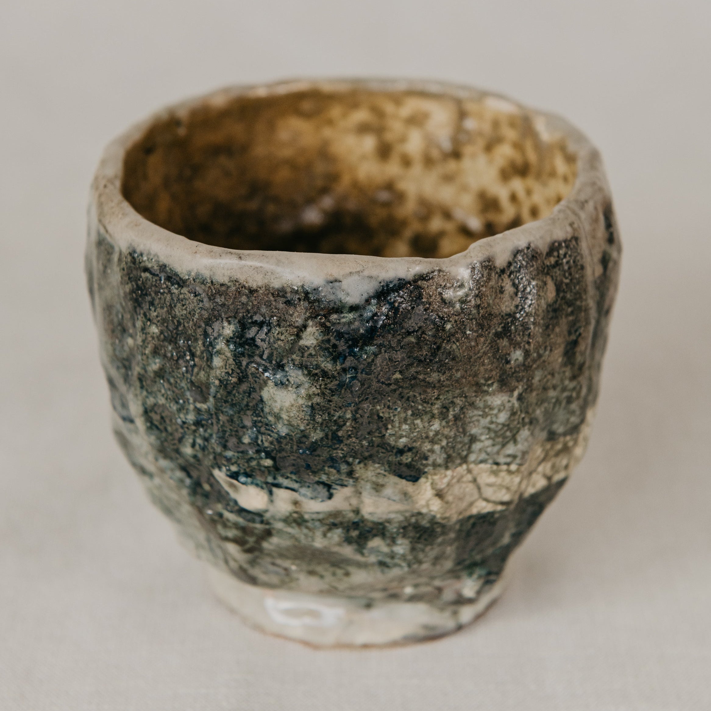 Vintage ceramic cup with a textured surface on a neutral background
