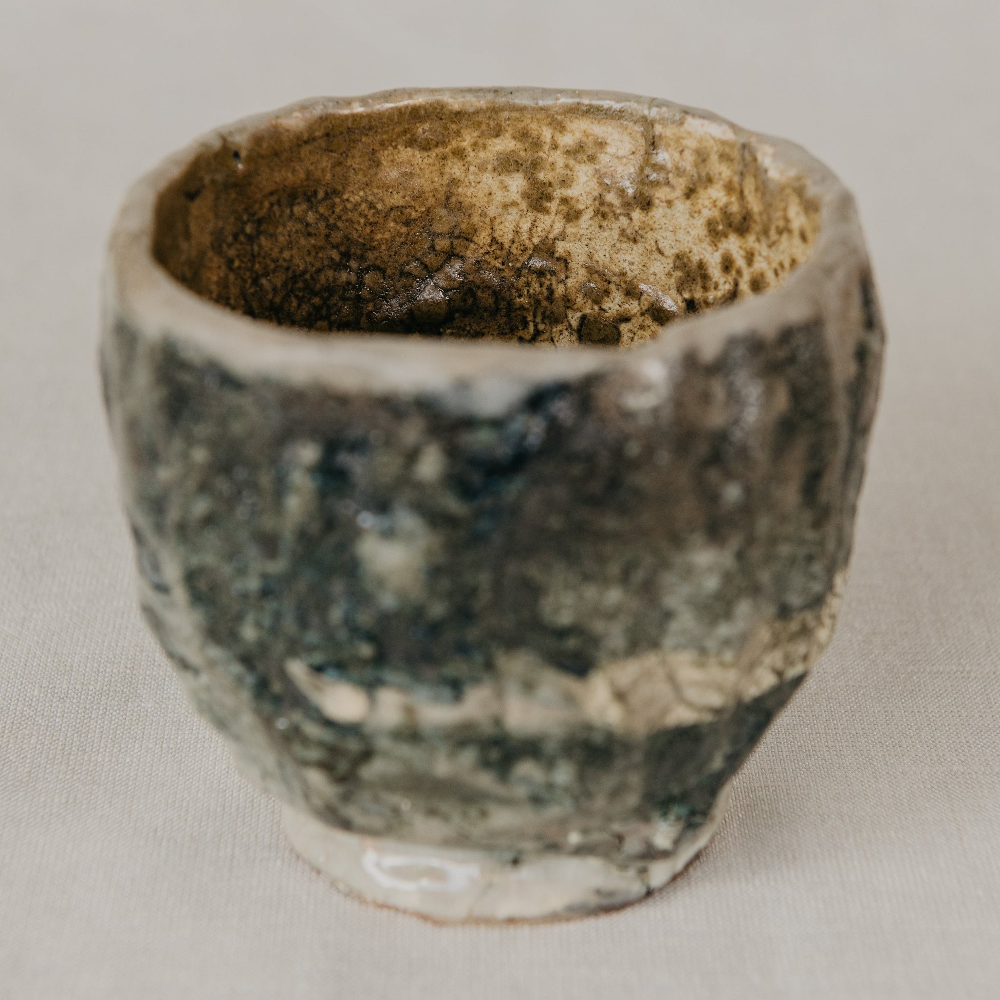 Small ceramic cup with a textured surface on a plain background